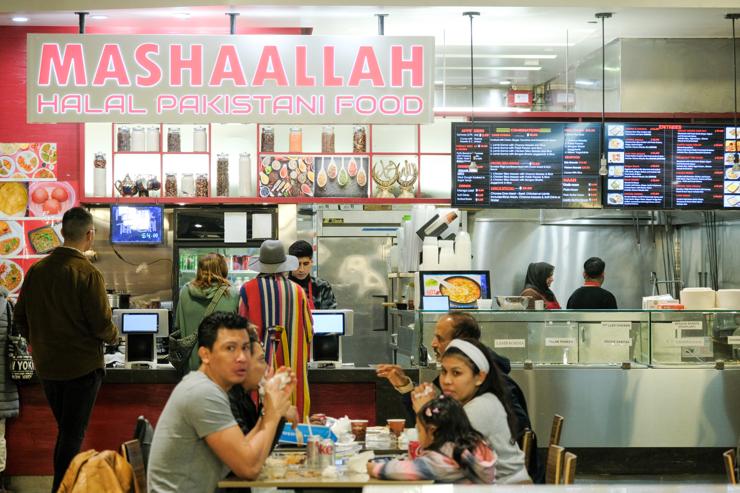 people dine in front of a halal pakistani restaurant stand