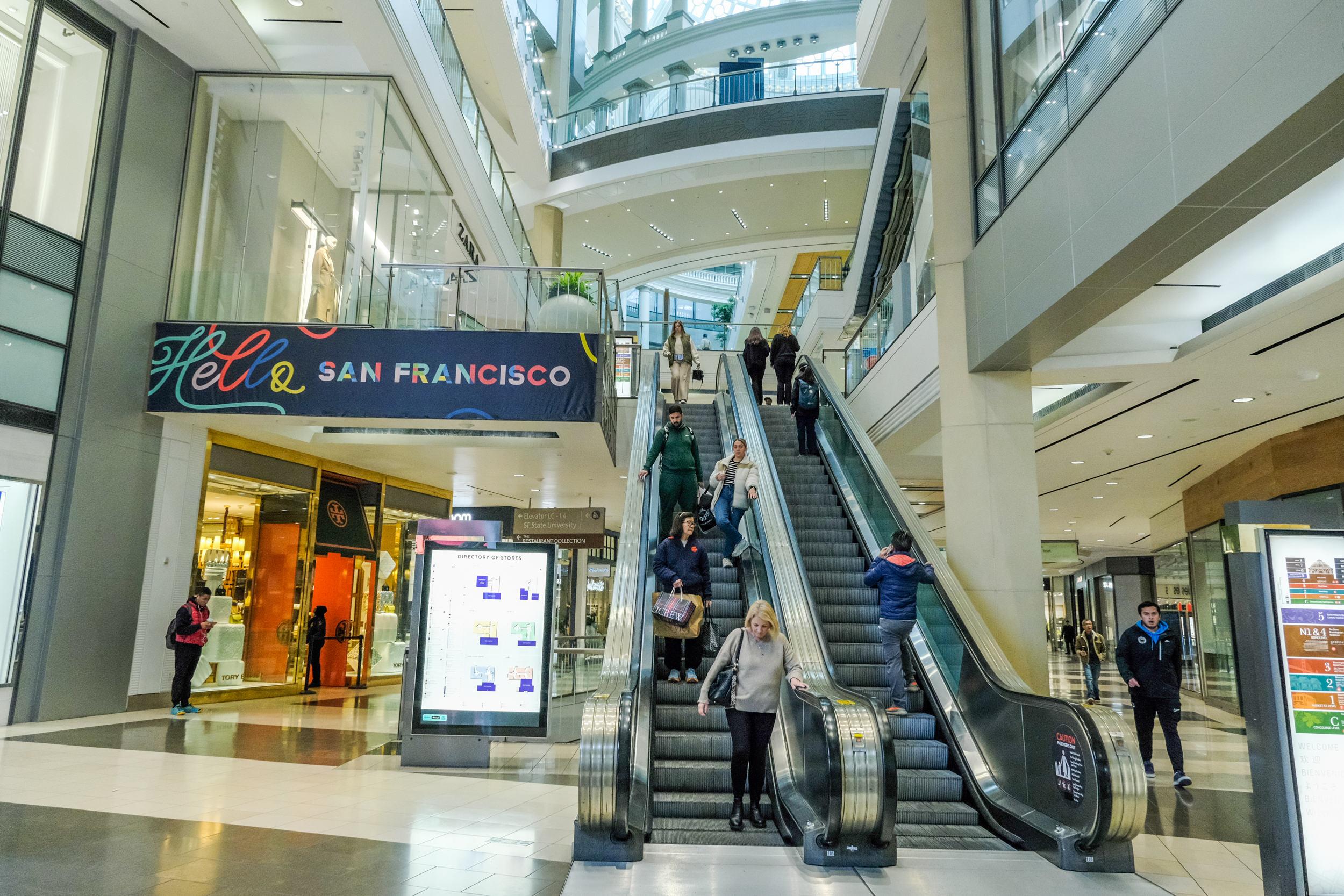 people ride escalator in a mall