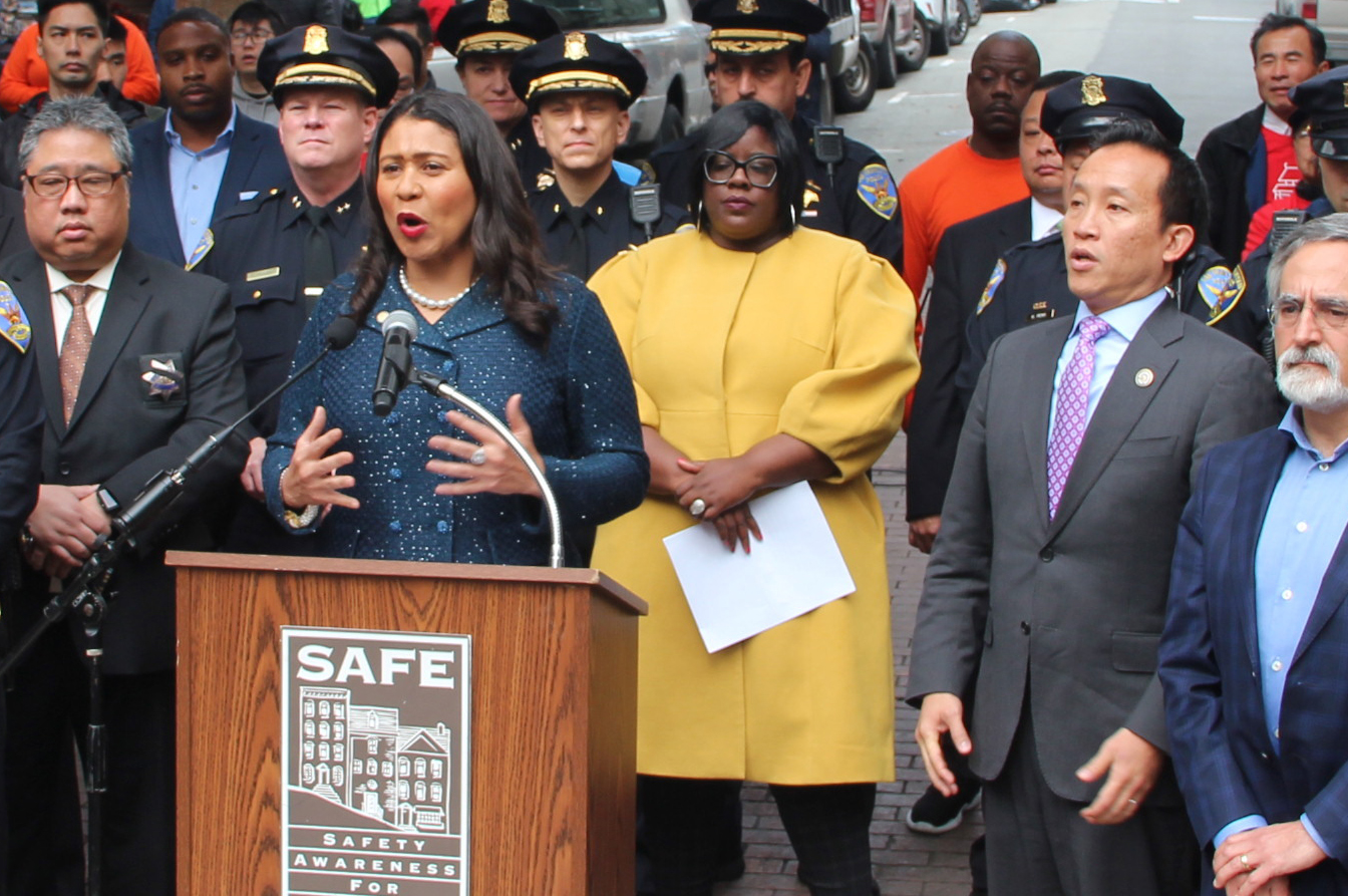 Kyra Worthy stands at a press conference with Mayor London Breed and other city officials.