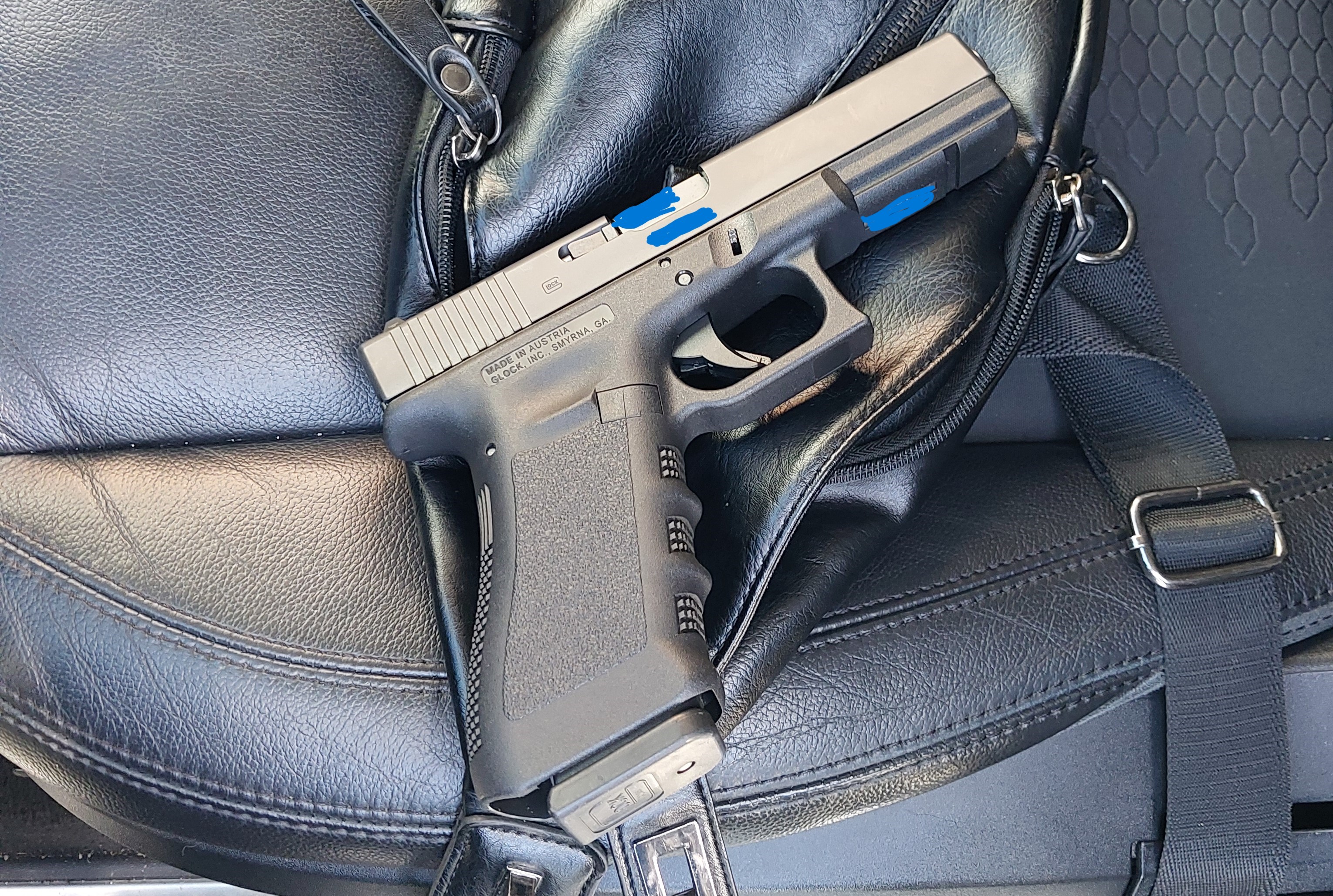 A black handgun pictured on black leather seat
