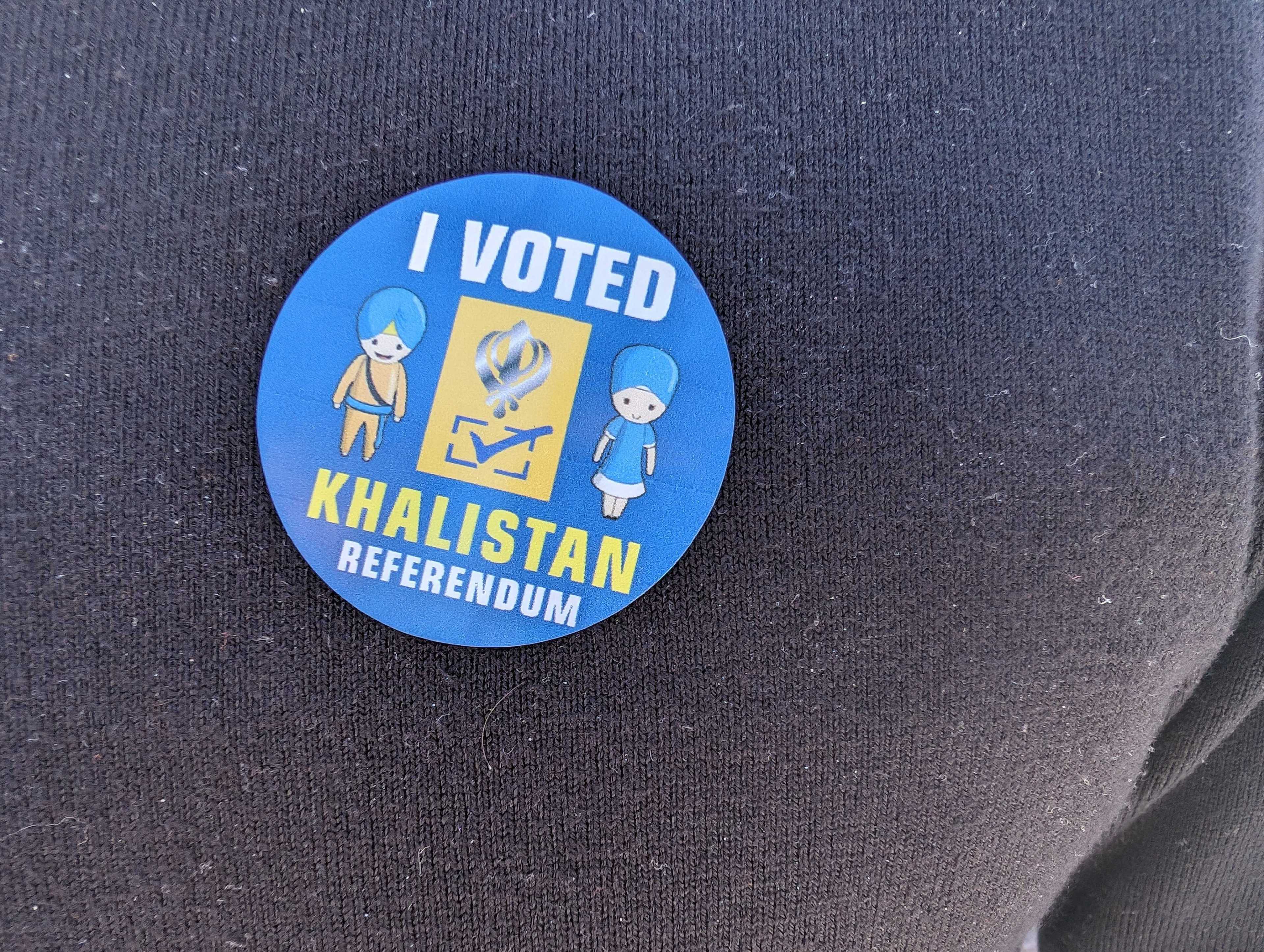 A blue sticker with images of two people on it, with white and yellow lettering reading I VOTED and KHALISTAN REFERENDUM
