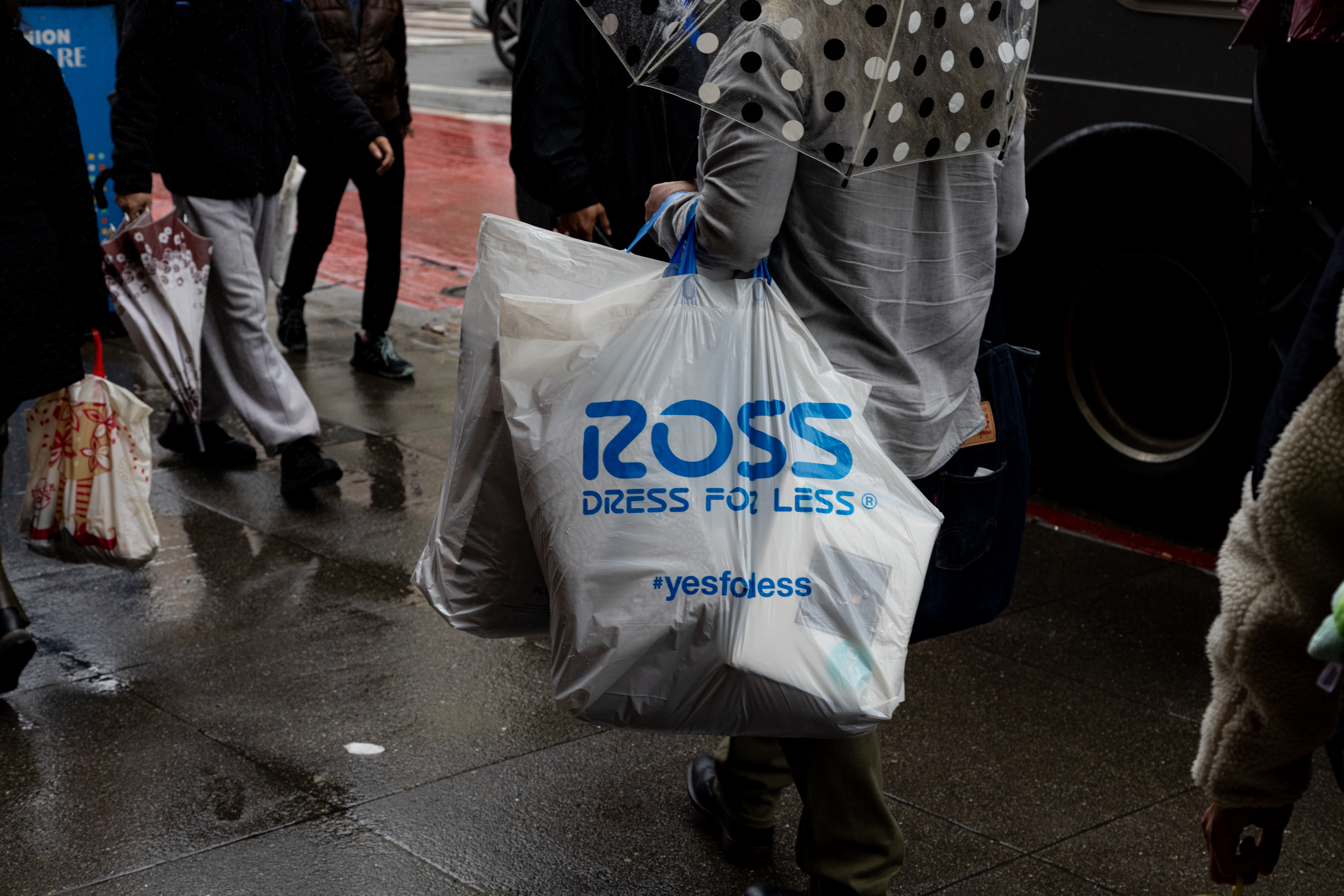 A person carries Ross shopping bags while walking on the sidewalk near Market and Fourth Streets.