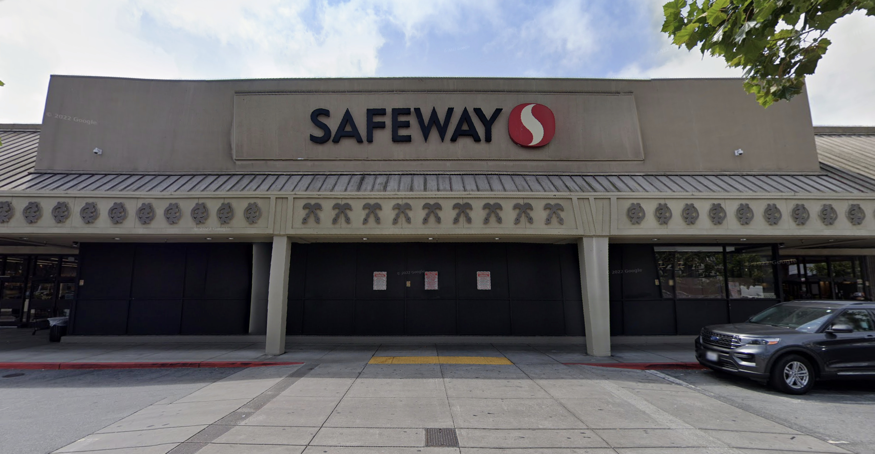 A exterior of a Safeway with cars to the right.