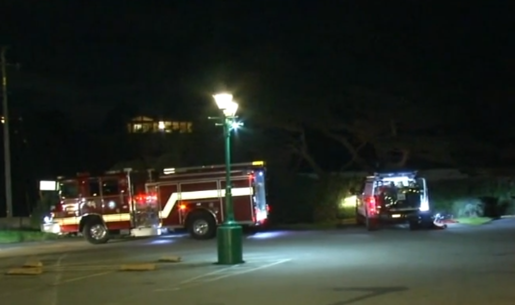 A fire truck and vehicle at night, lit by a streetlamp, possibly at an emergency scene.