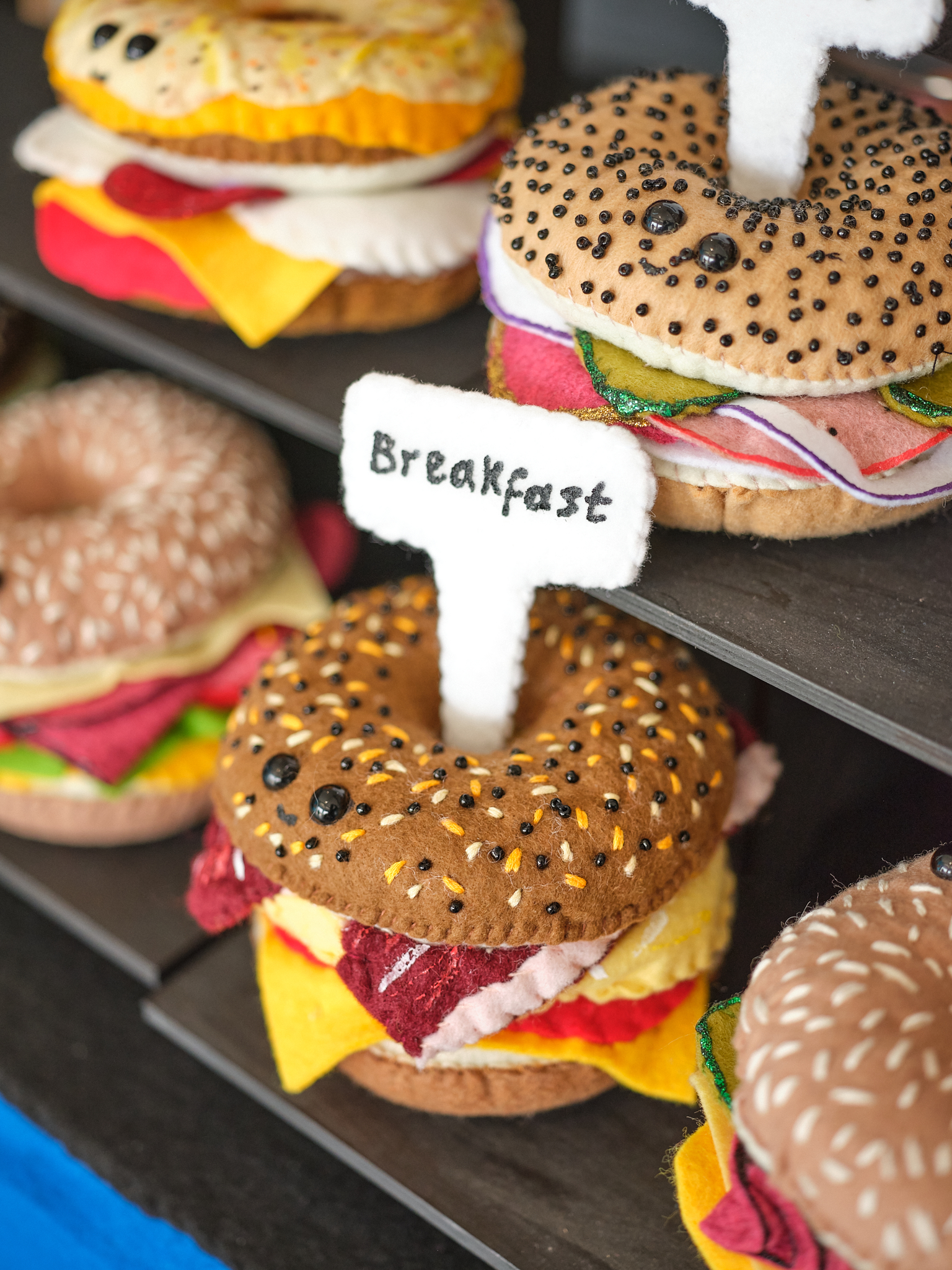 Breakfast bagels made out of felt stand on a shelf.
