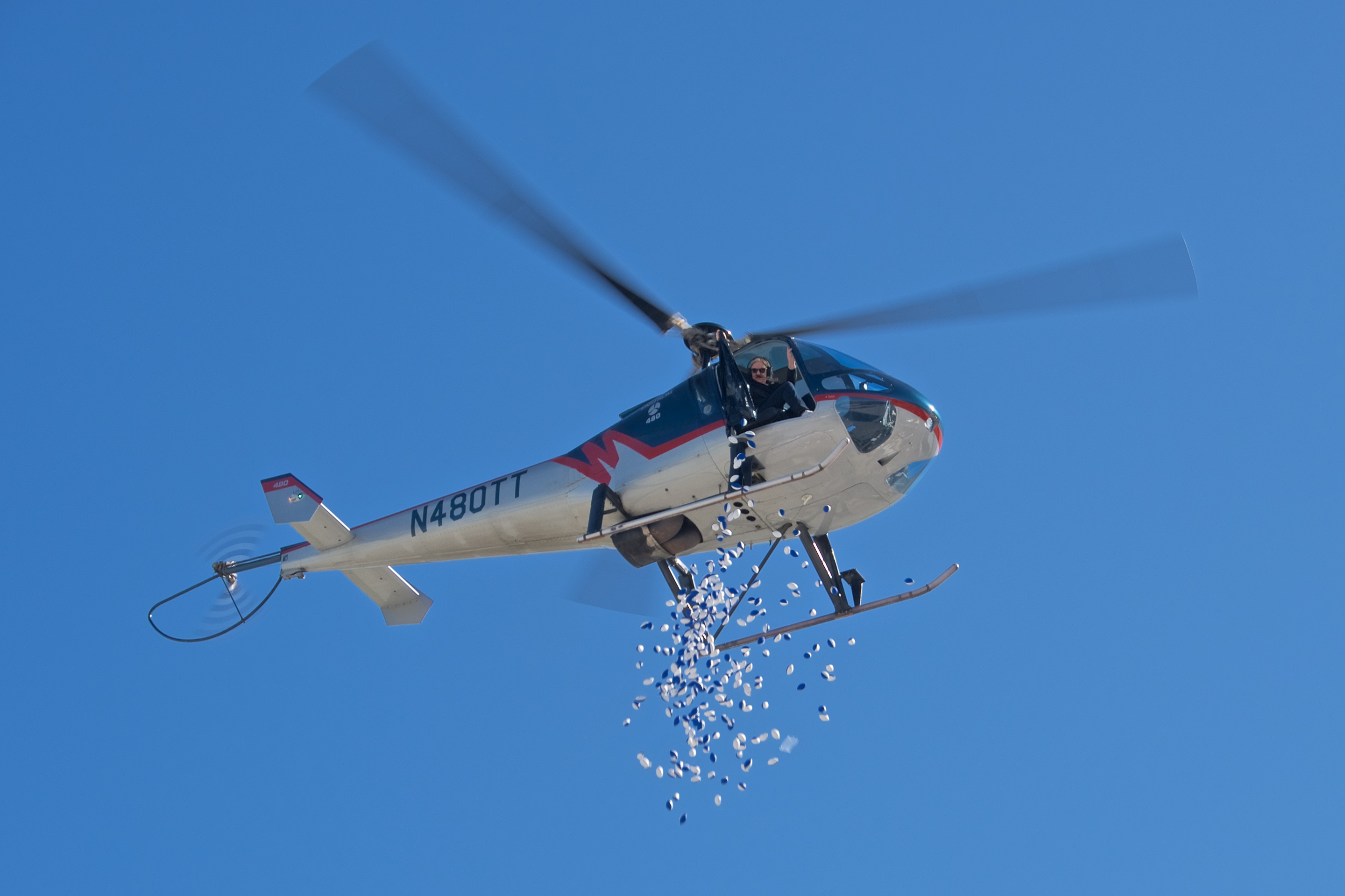 A flying helicopter  drops foam blue mini footballs from the sky. 