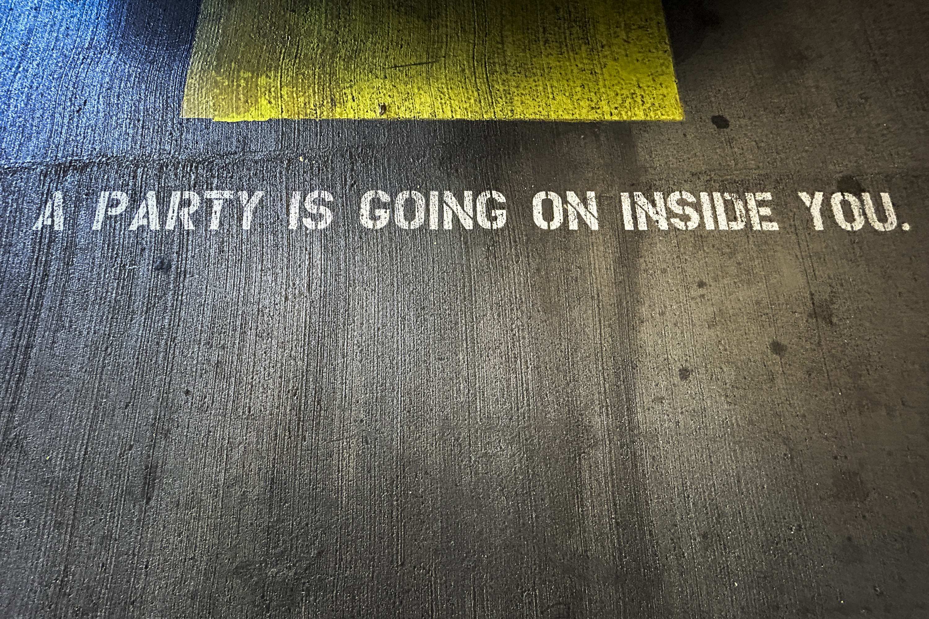 stenciled text on a parking garage space saying &quot;a party is going on inside you&quot;