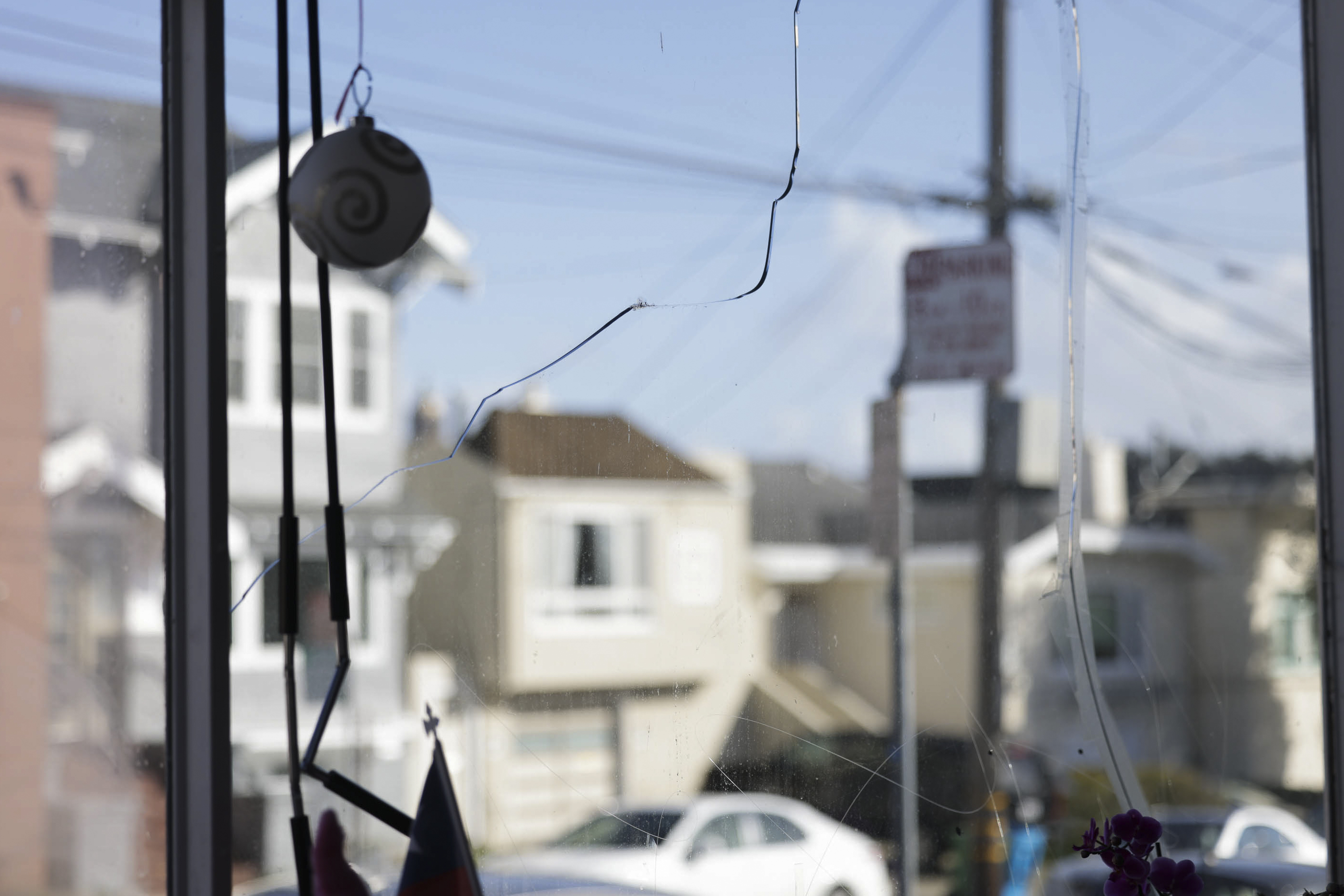 The image shows a cracked window with blurry street view and hanging decorations.