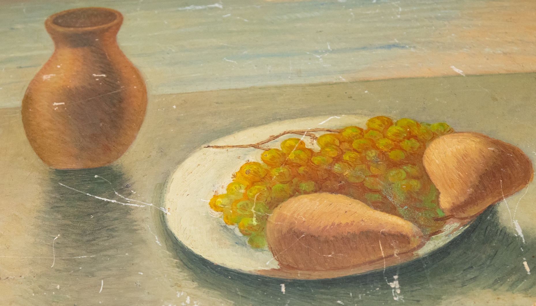 A painting depicts a clay pot, a plate of grapes, and two pieces of bread on a table.