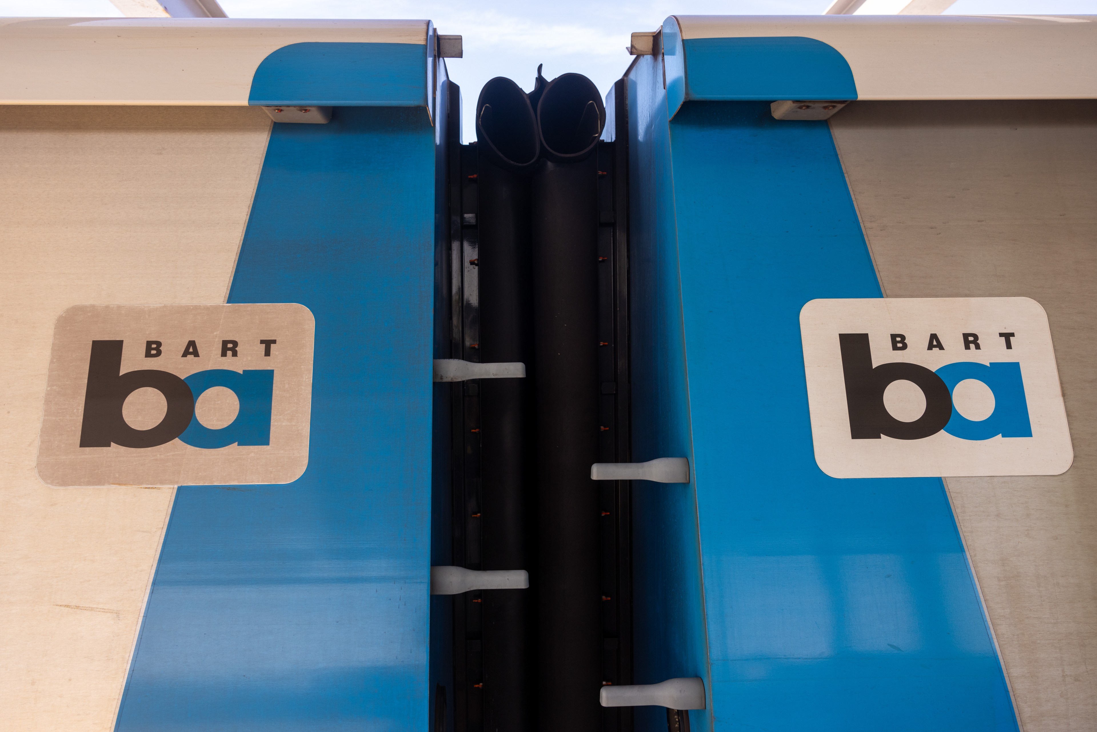 A photo shows the space between two BART train carriages.