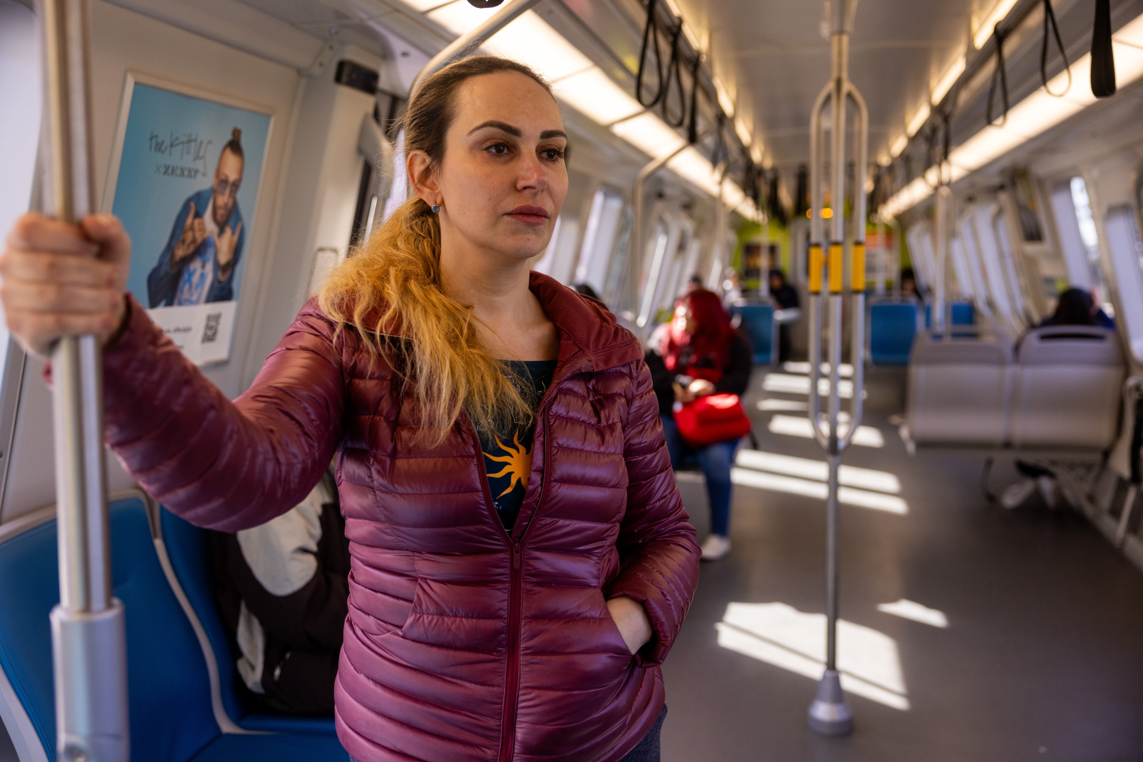 A woman stands inside of a BART car.