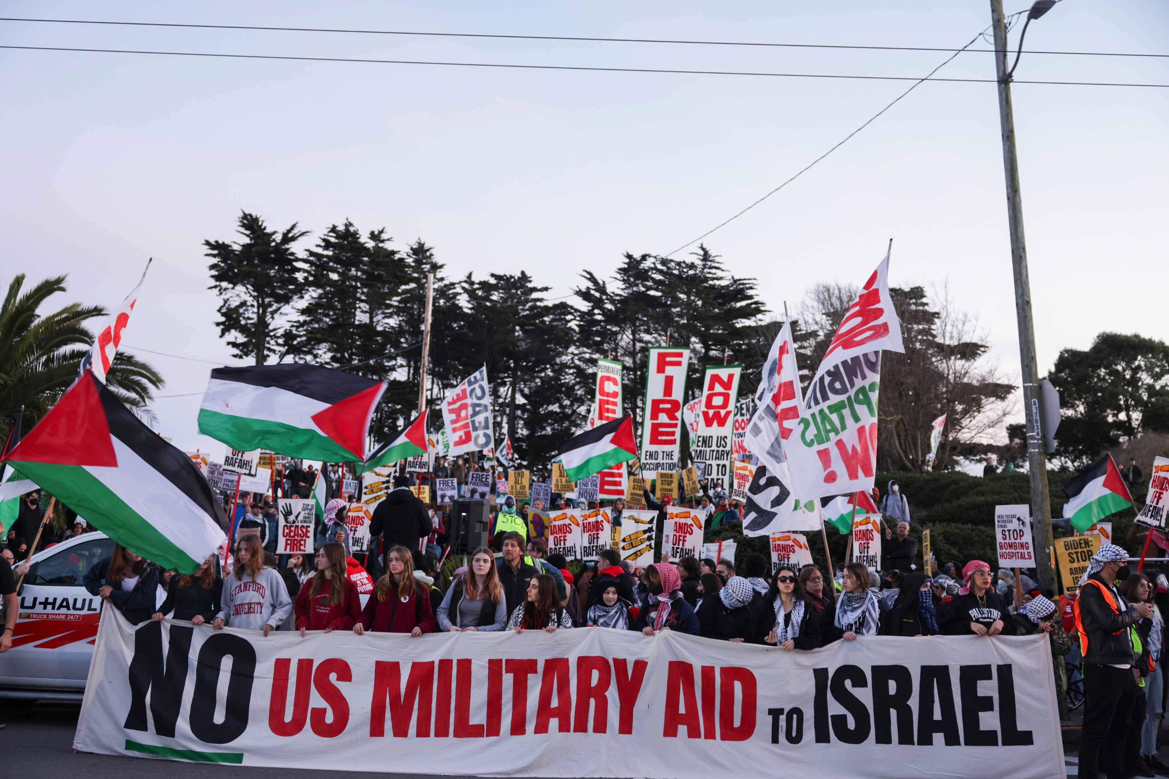 Protesters march down street carring a banner that states no us military aid in israel