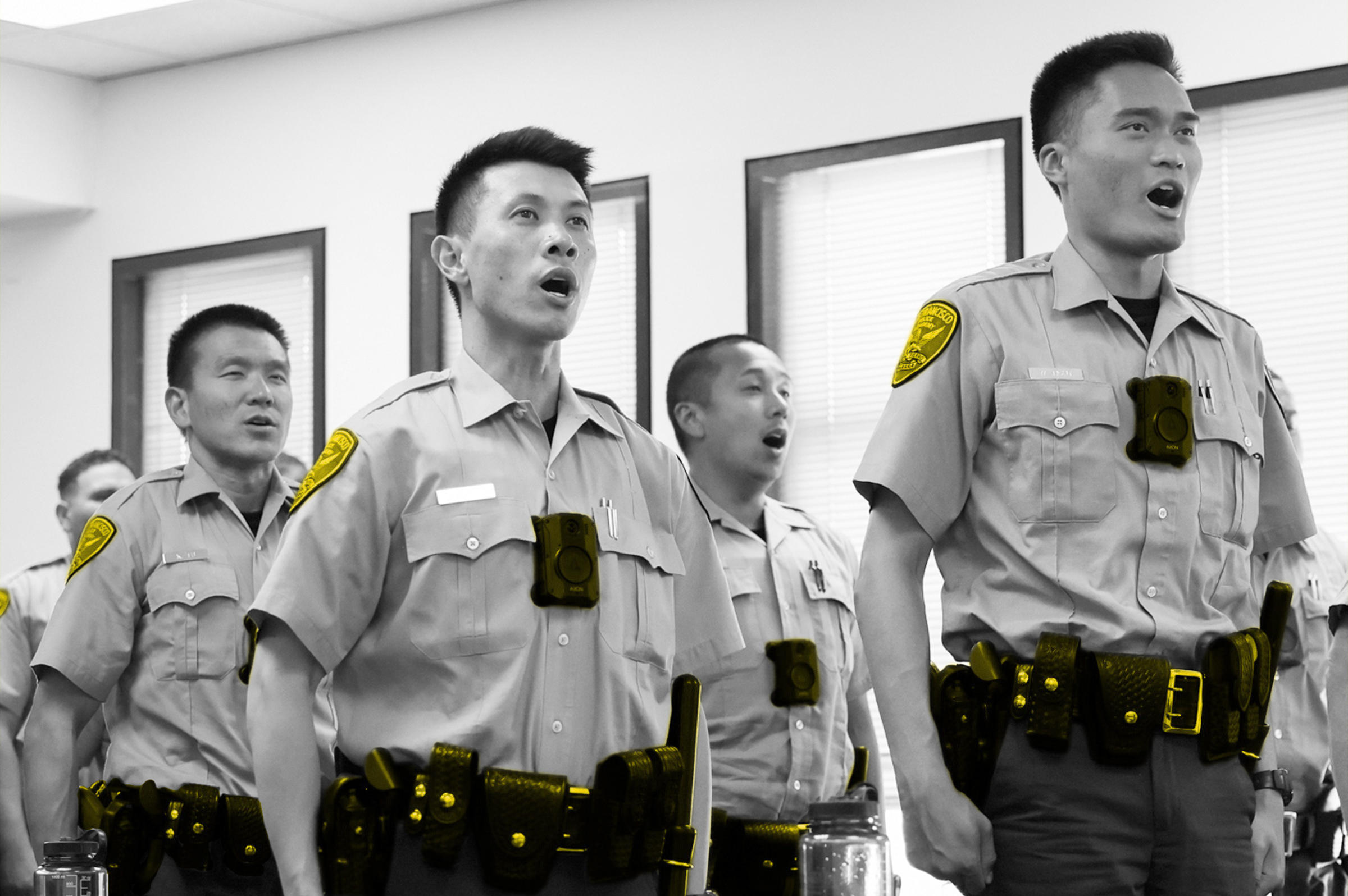 Uniformed officers stand in formation, reciting an oath with focused expressions.