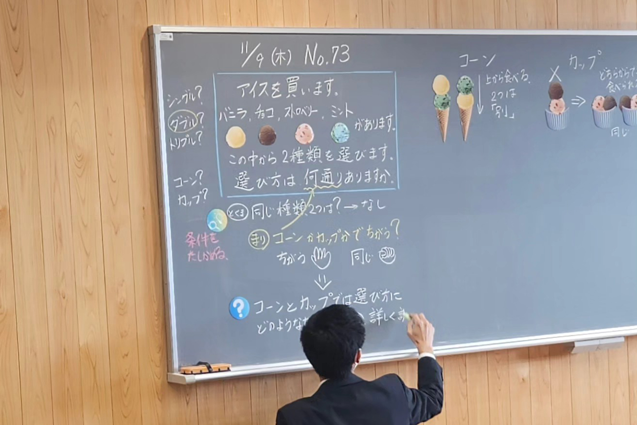 A Japanese school teacher writes on a blackboard that features drawings of ice cream.