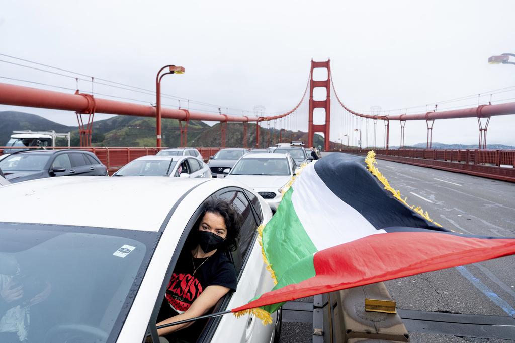 Ashley Corri holds a Palestinian flag while parked on the Golden Gate Bridge.