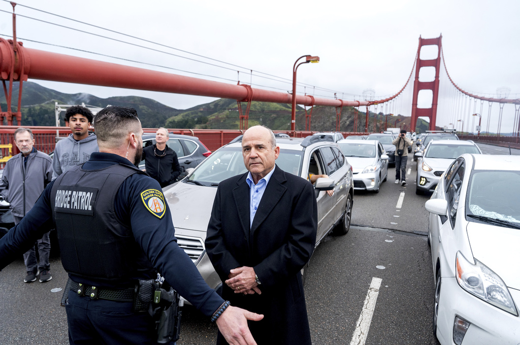 A police officer keeps a driver separated from demonstrators as they block traffic on the Golden Gate Bridge.
