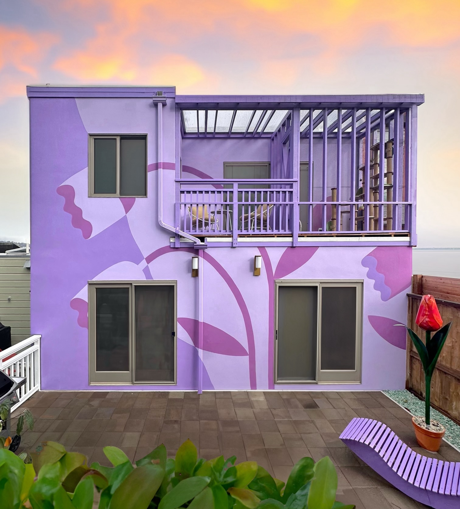 A two-story flattop purple house features a tulip mural on its backside. 