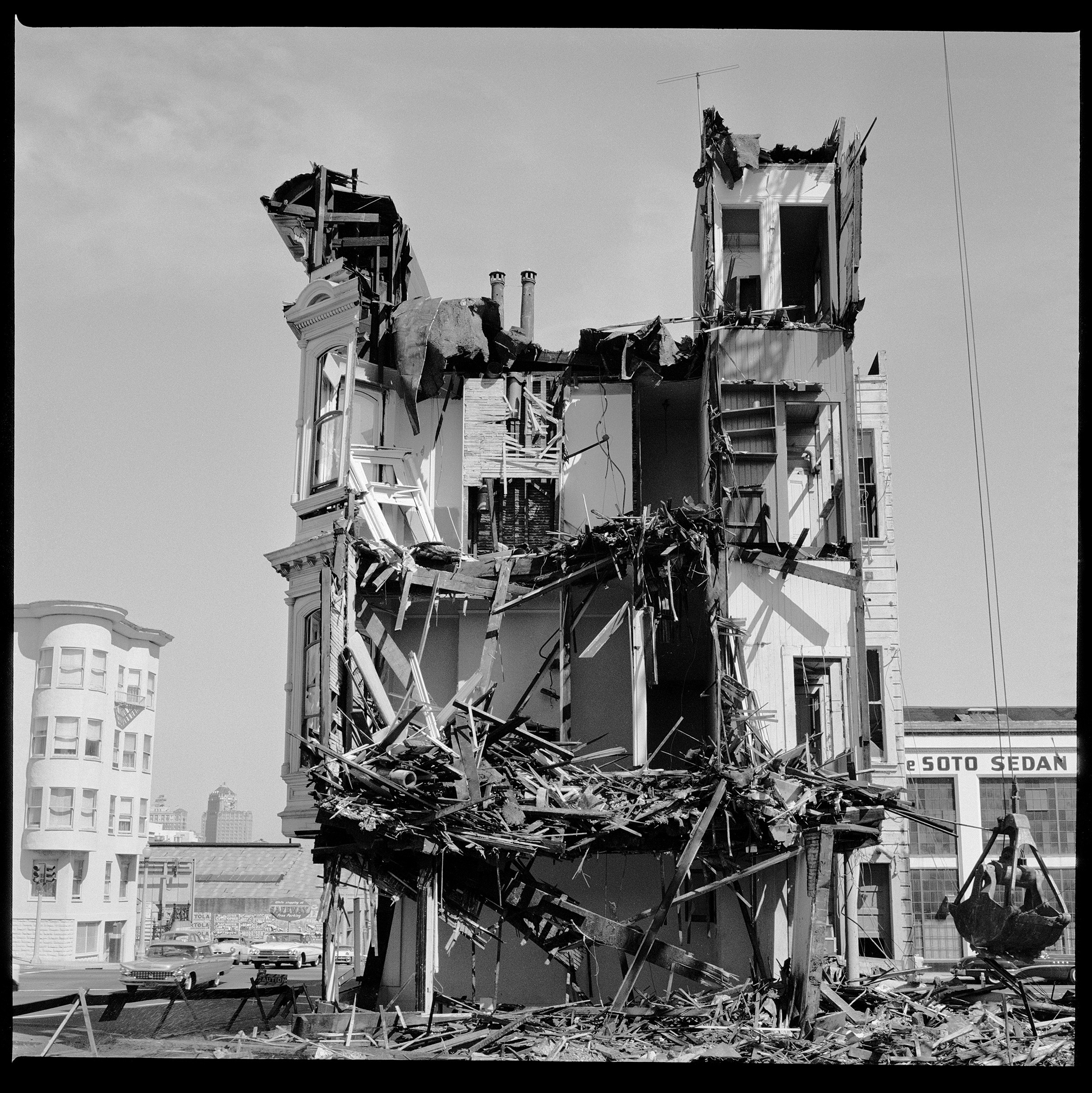 A partially demolished building with exposed interiors and debris around it.