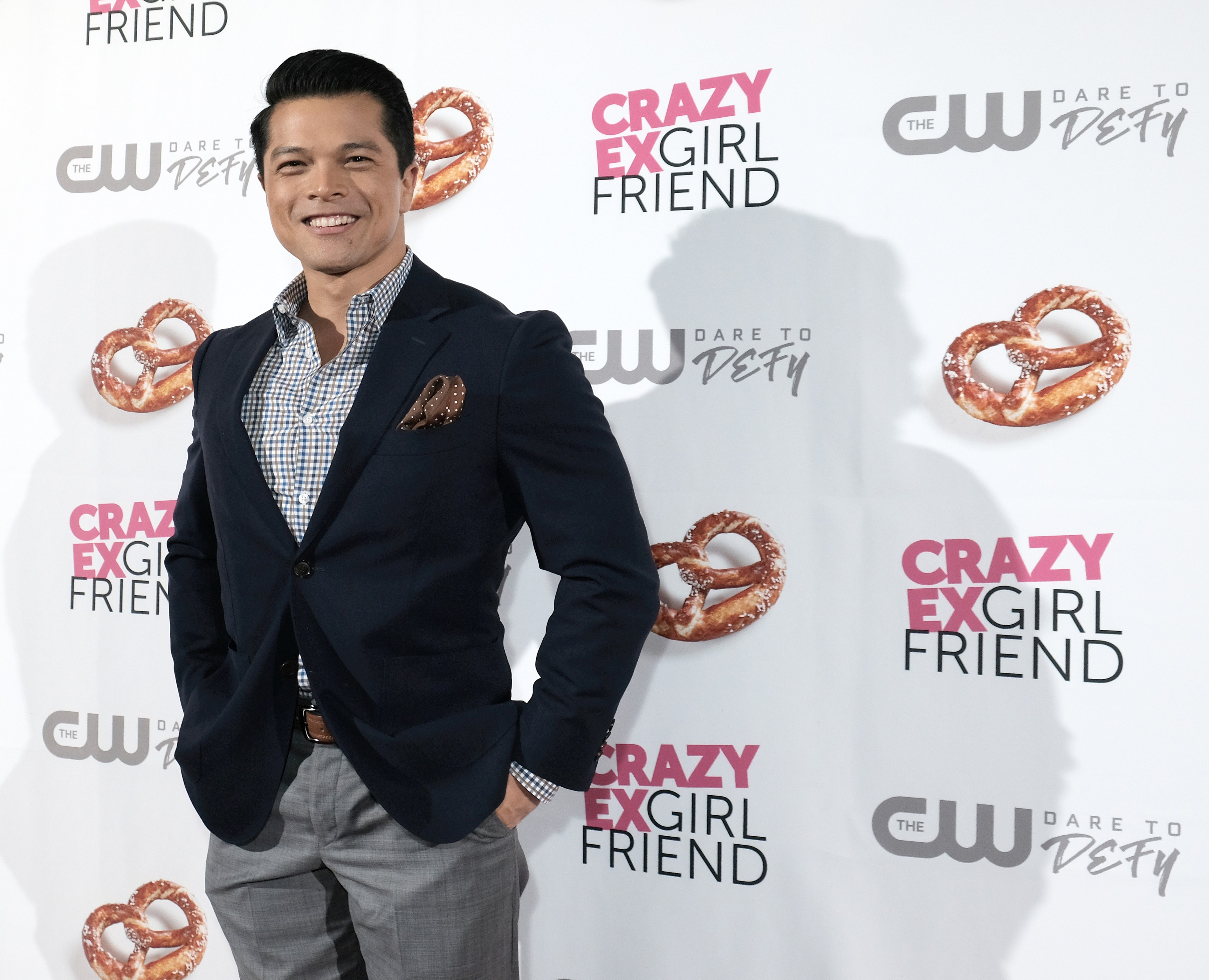 A smiling man in a sports coat poses at a TV show premiere.