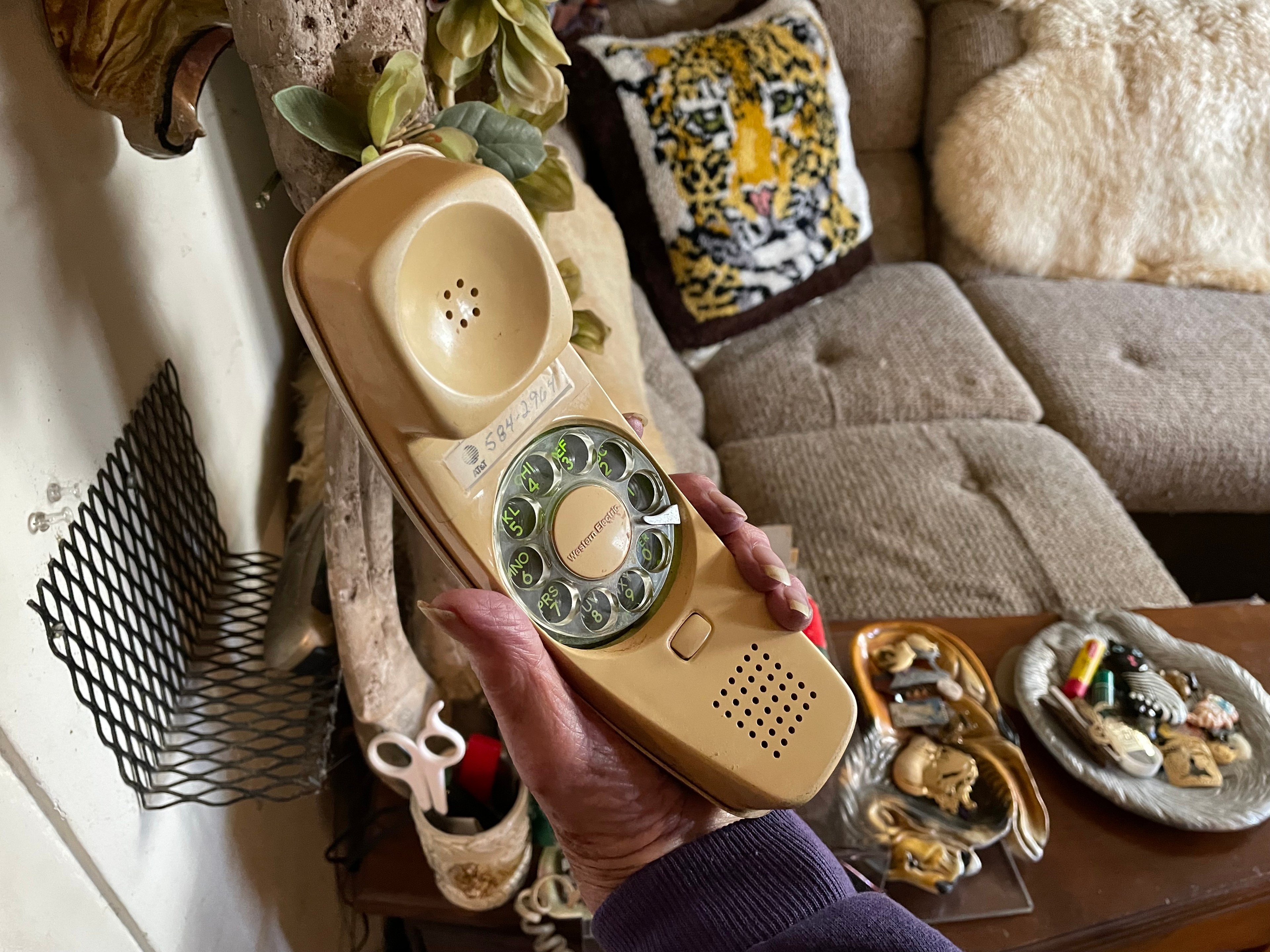 An old woman shows a landline phone's rotary dial.