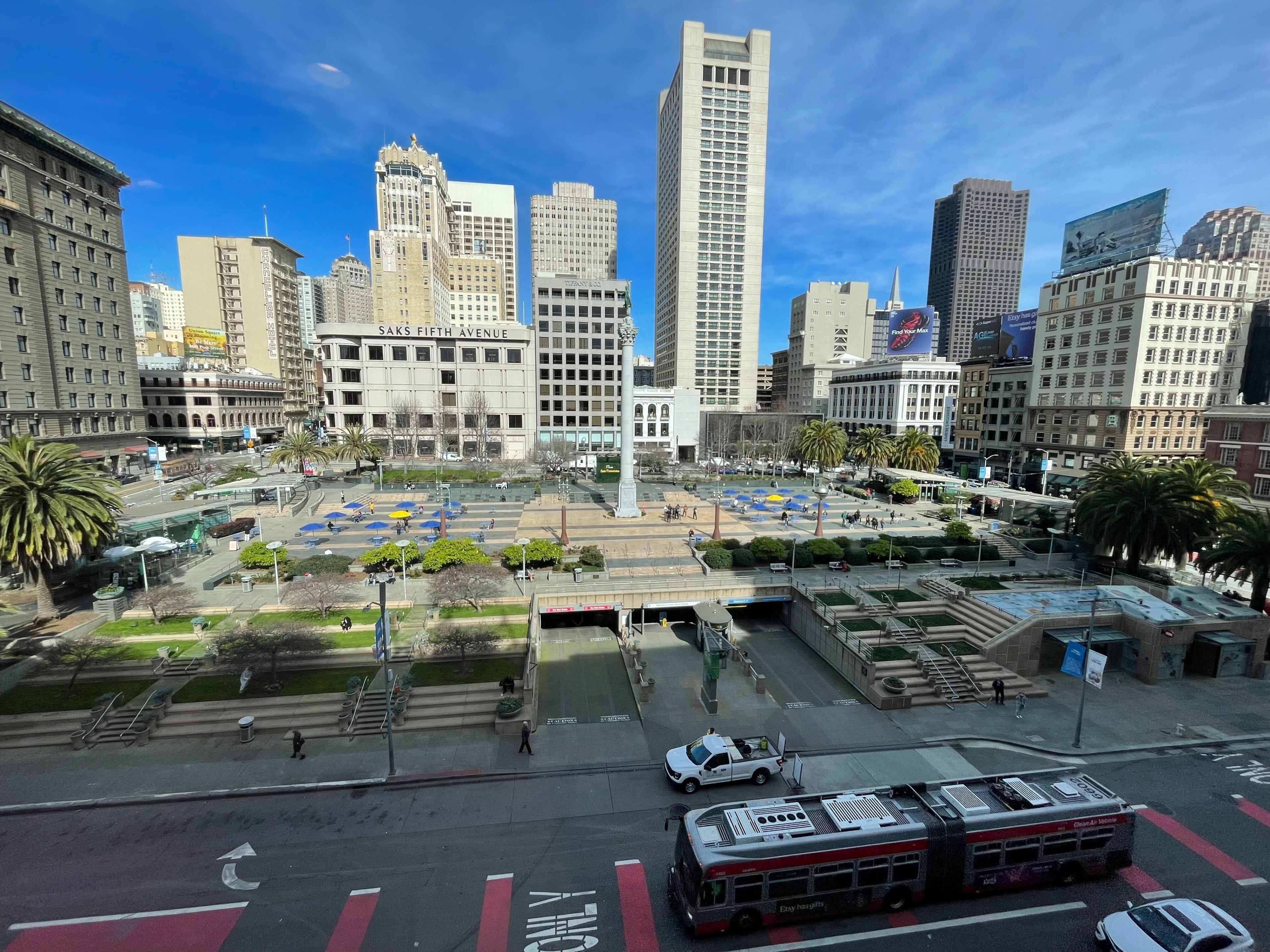 A city skyline and shaded streets surround a sunlit central plaza.