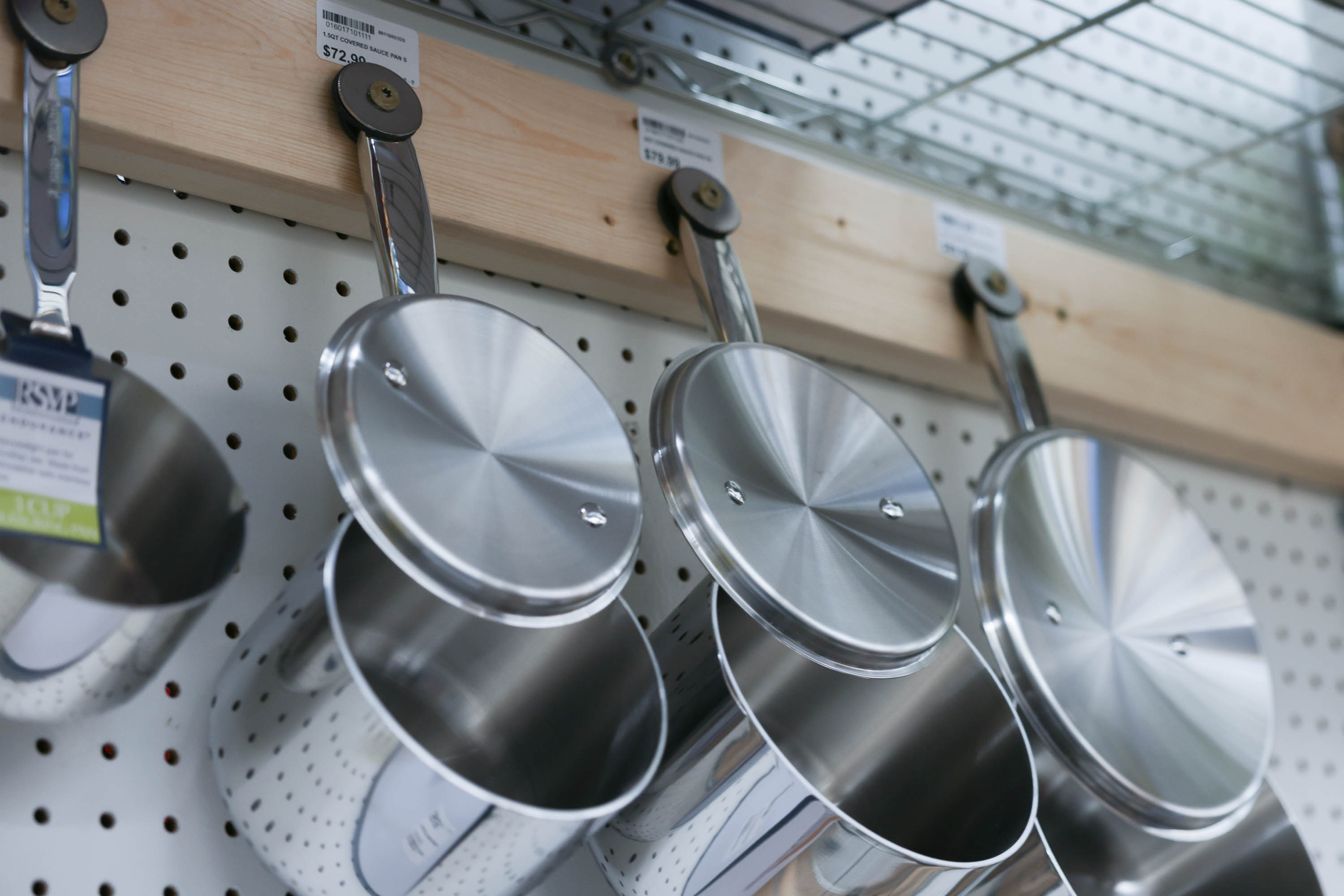 Three pans hang below a metal shelf