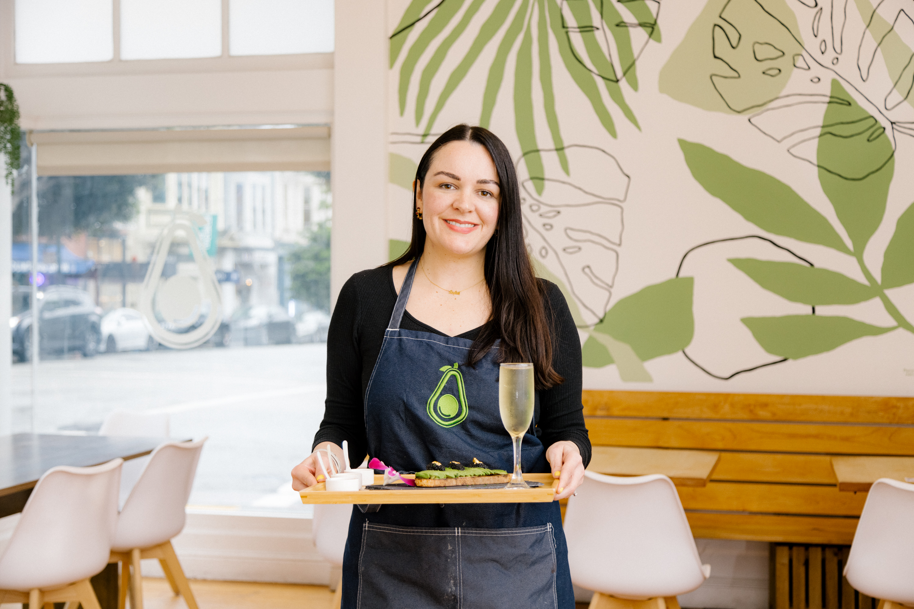 Avotoasty owner Sofia Pinzon stands in her avocado toast cafe holding a tray. 
