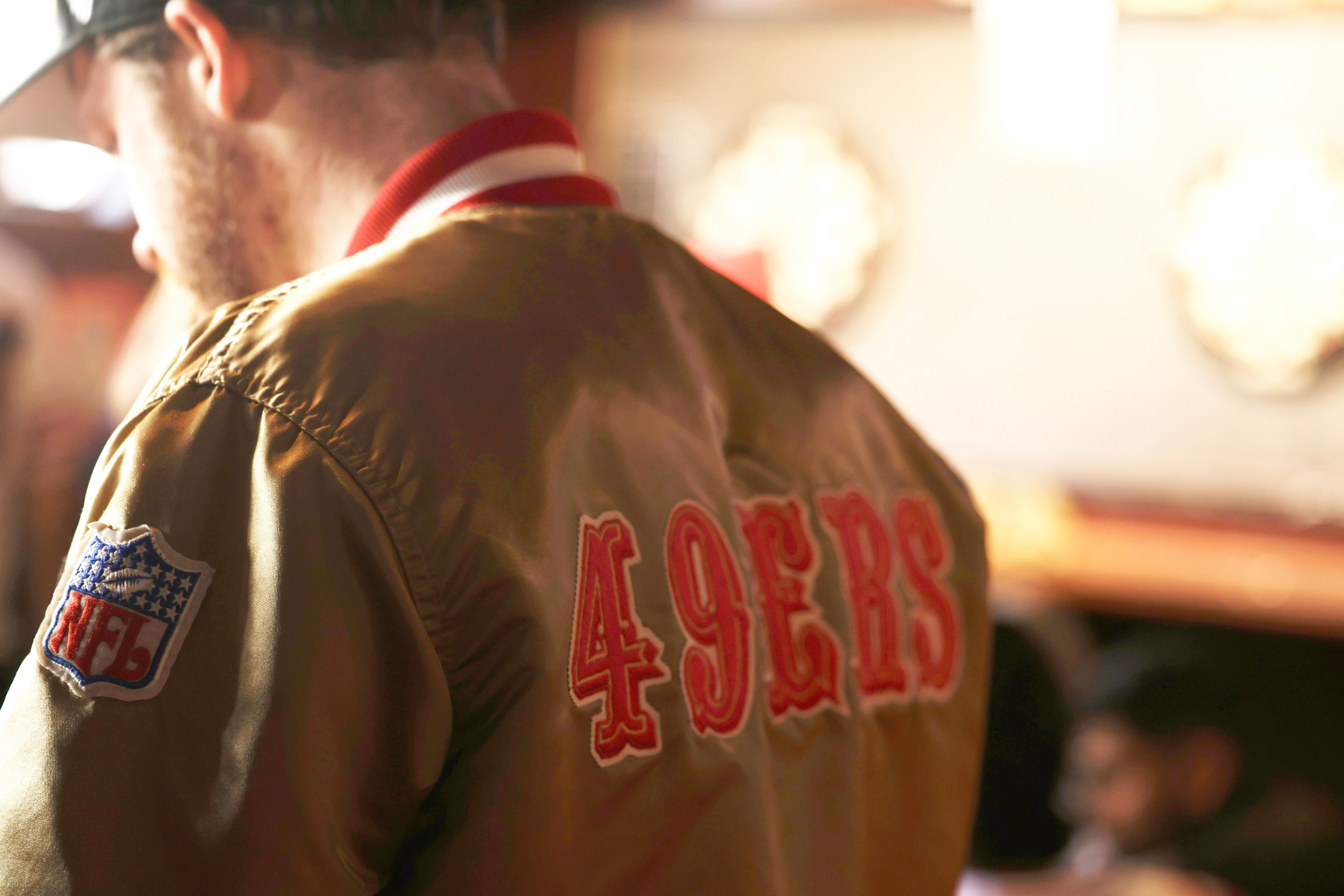 A man wearing a gold 49ers starter jacket