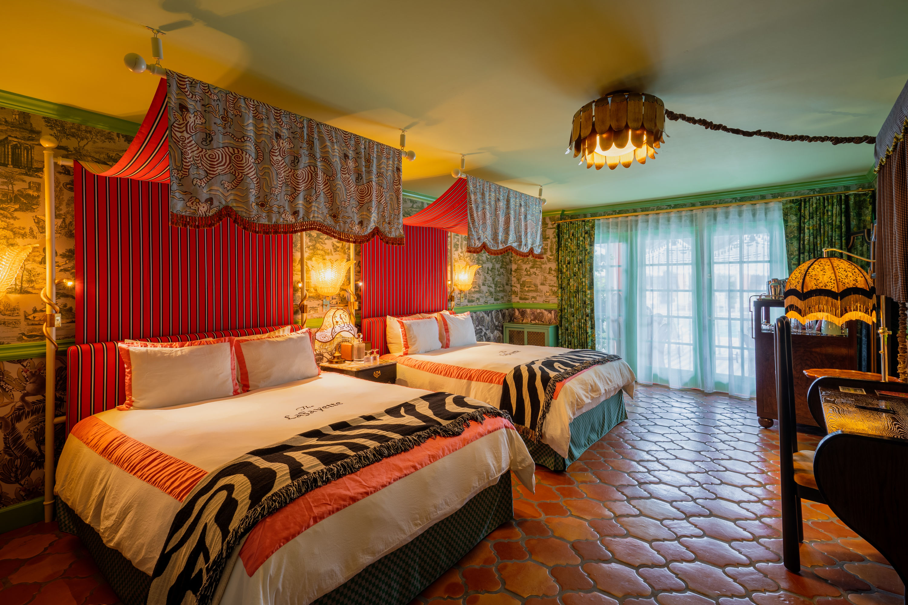A room with two beds with dragon drapery and a red tiled floor