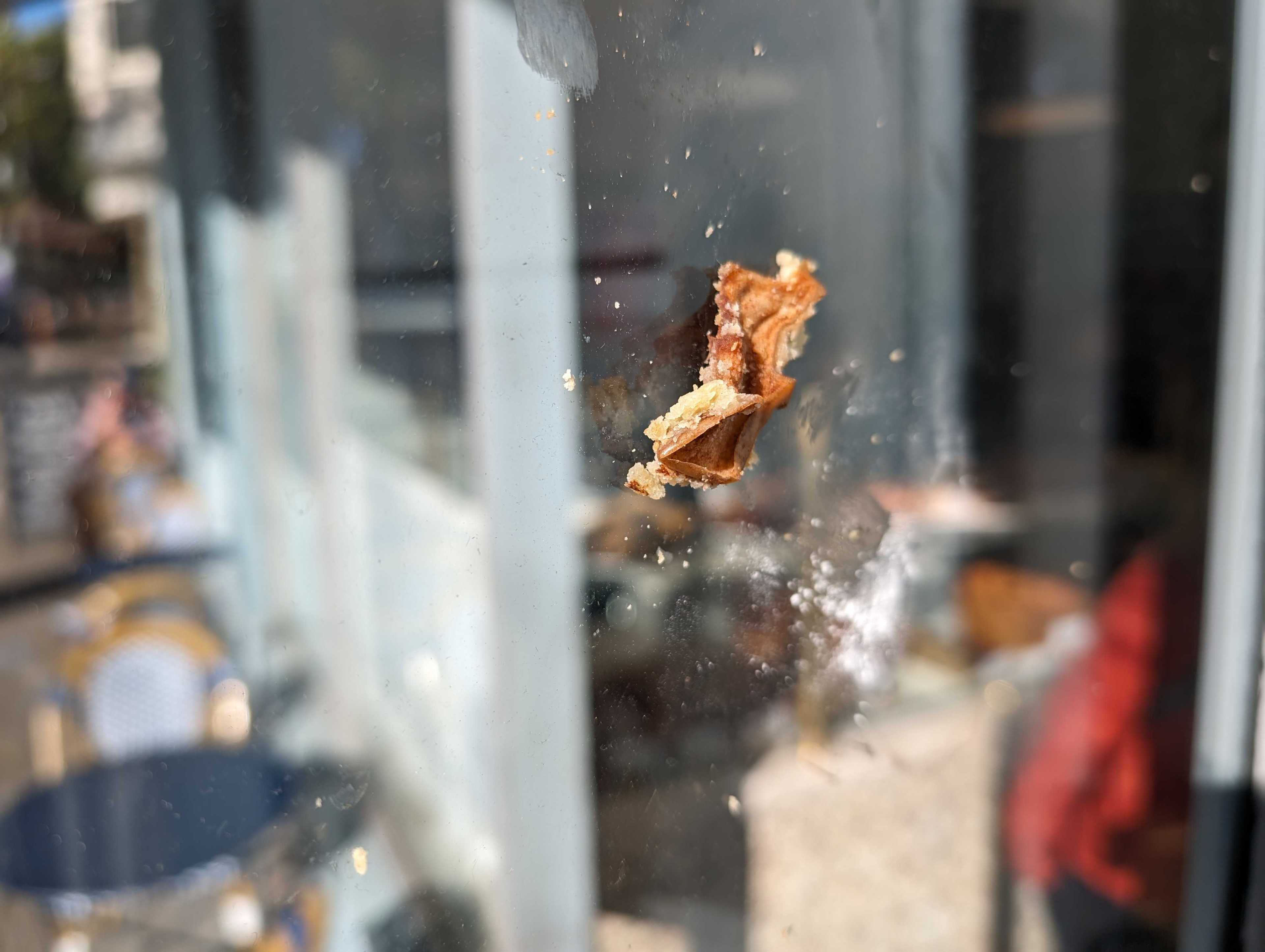 A small piece of pastry sticks to a cafe's glass window in bright sunshine