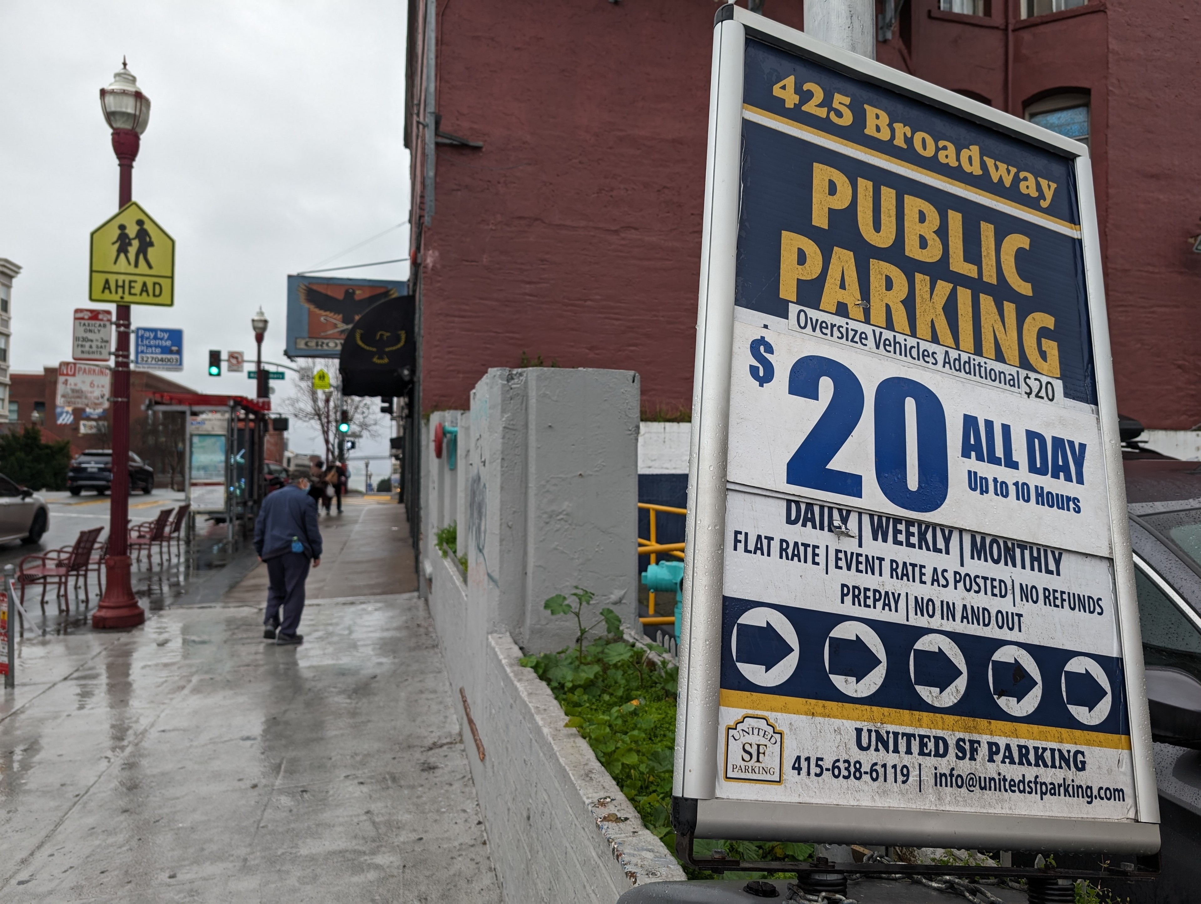 A sign offers public parking at daily, weekly and monthly rates at an off-street parking lot
