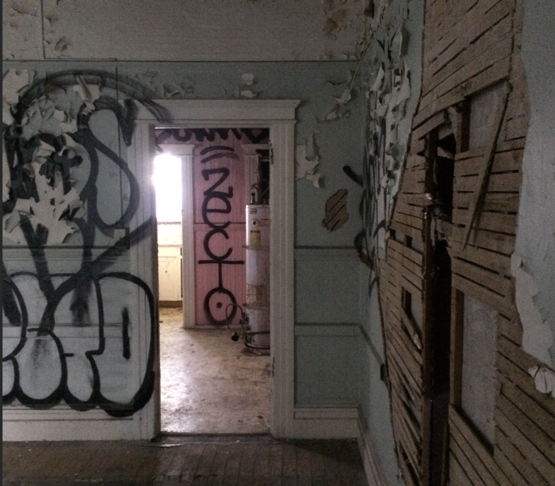An empty apartment room damaged by a fire is covered in graffiti.