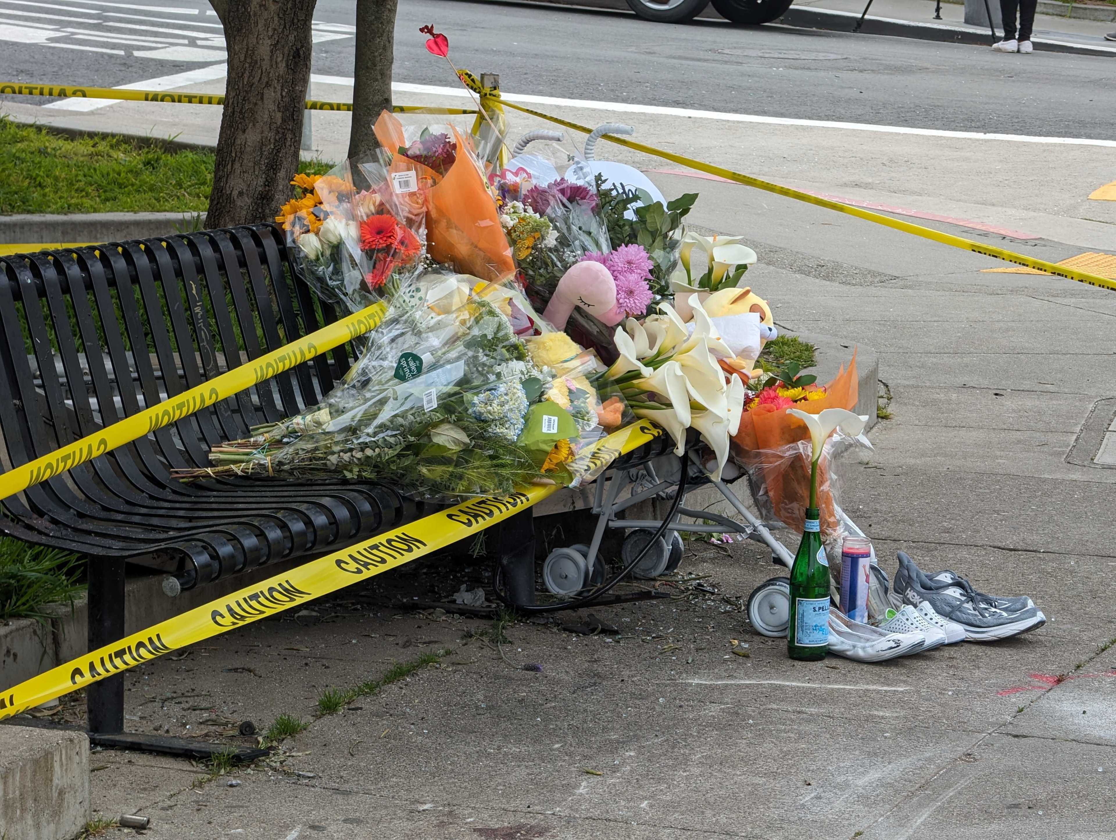 A sidewalk memorial with flowers, candles, and personal items, cordoned off by caution tape.