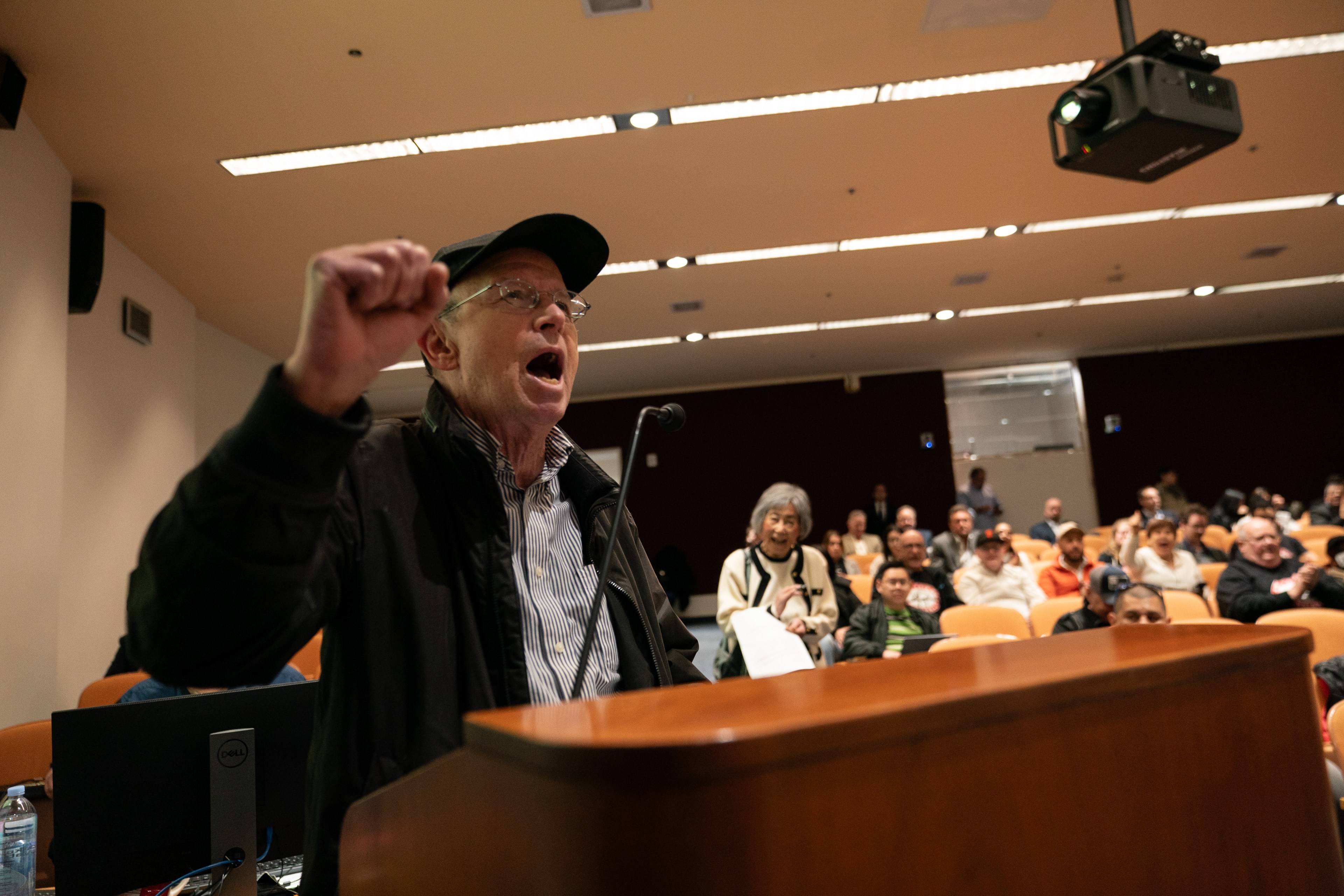 man with hat shouting at a lectern