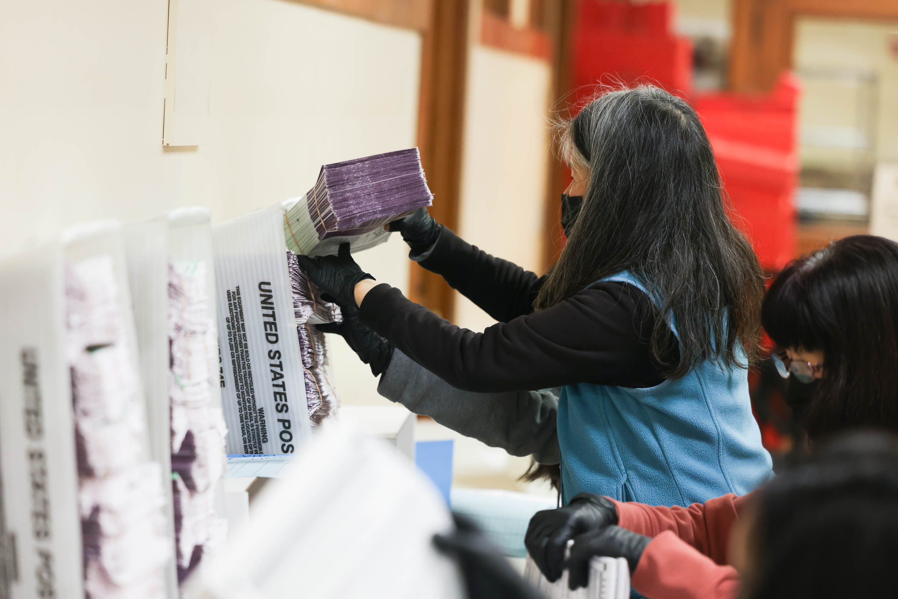 A worker in gloves sorts ballots.