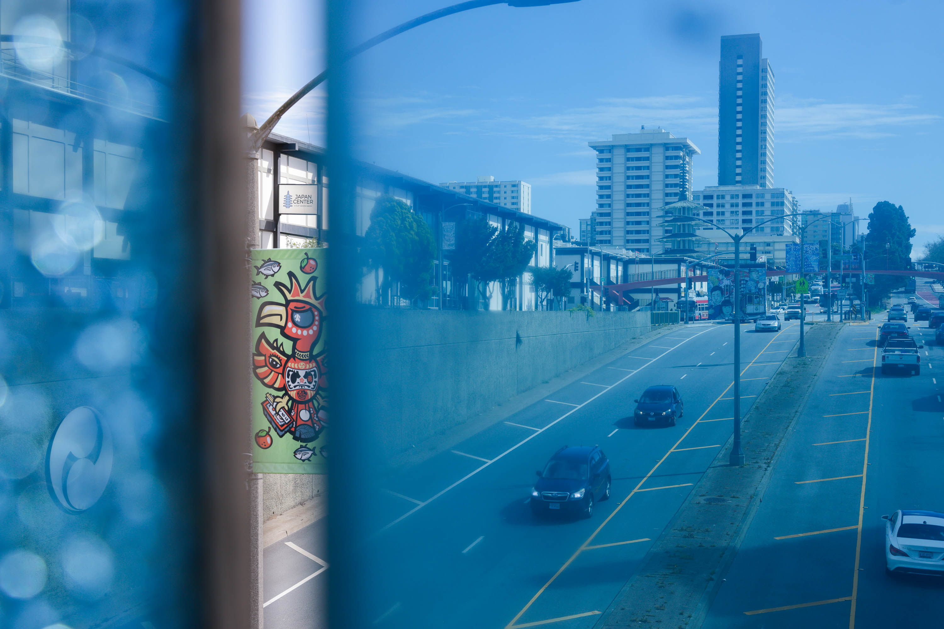 A cityscape with a road, colorful graffiti, moving cars, buildings, and a clear blue sky.