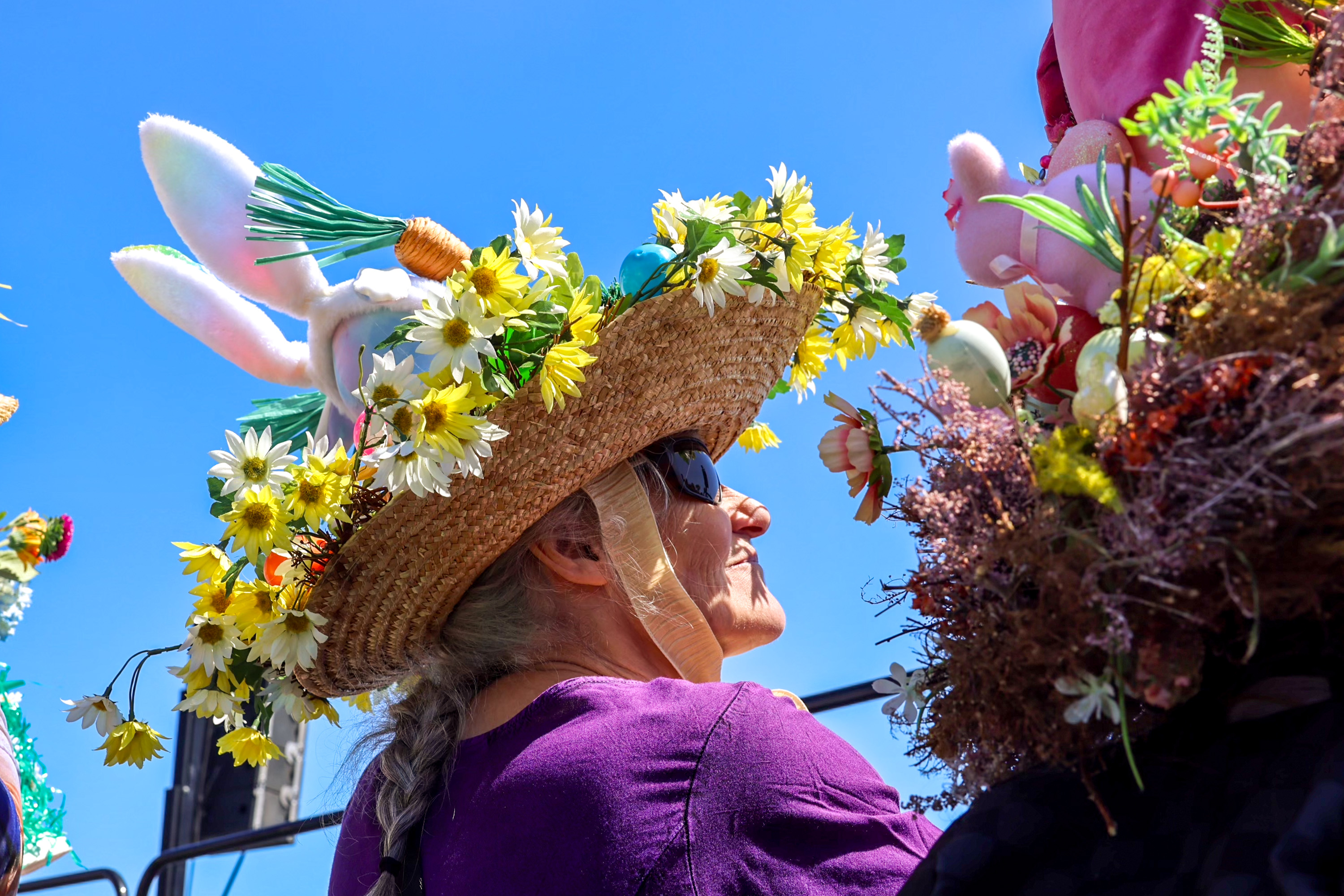 A person in a flower-adorned hat with bunny ears under a clear blue sky.