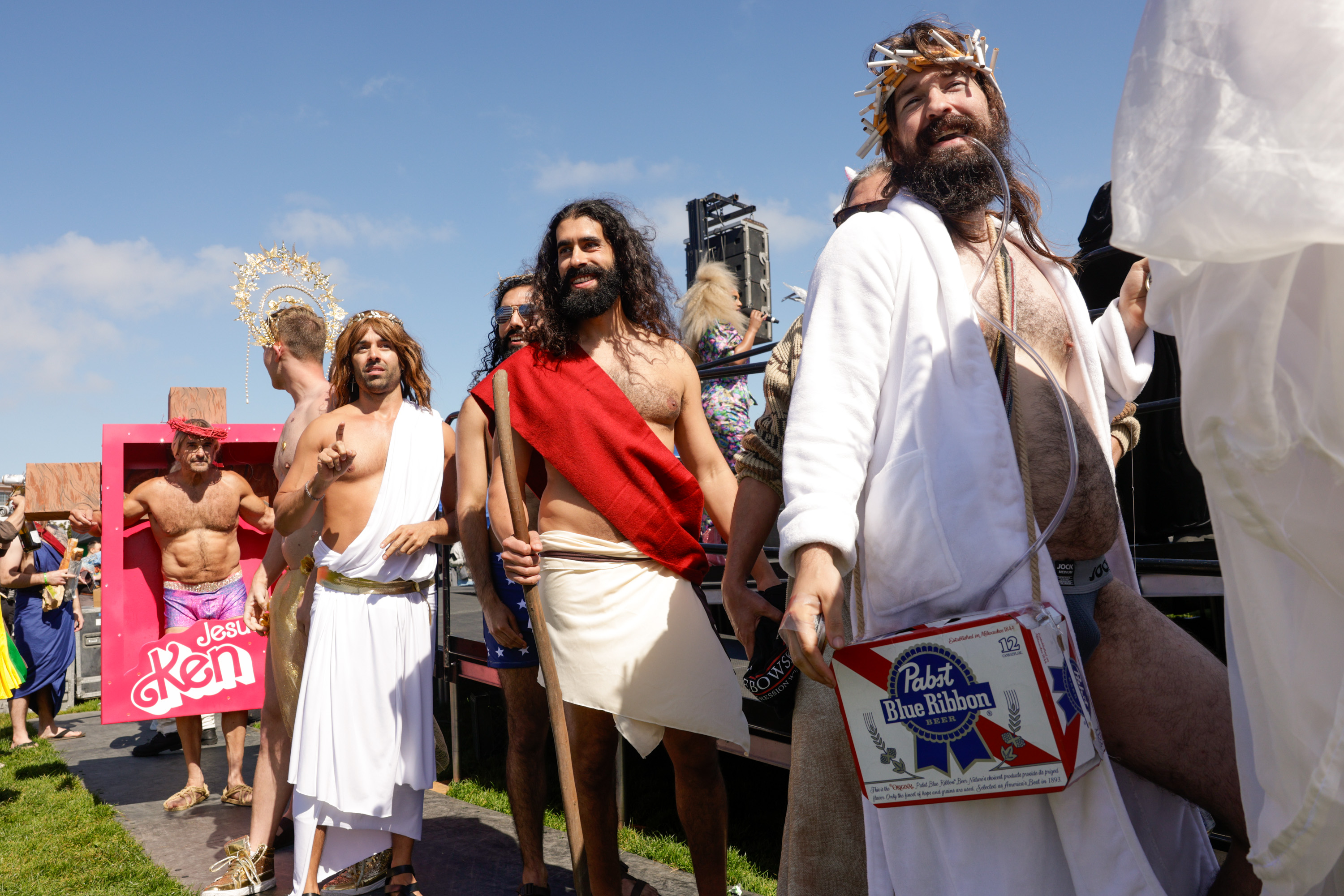 A group of people in white robes and fake beards, portraying different interpretations of Jesus, gather for an event.