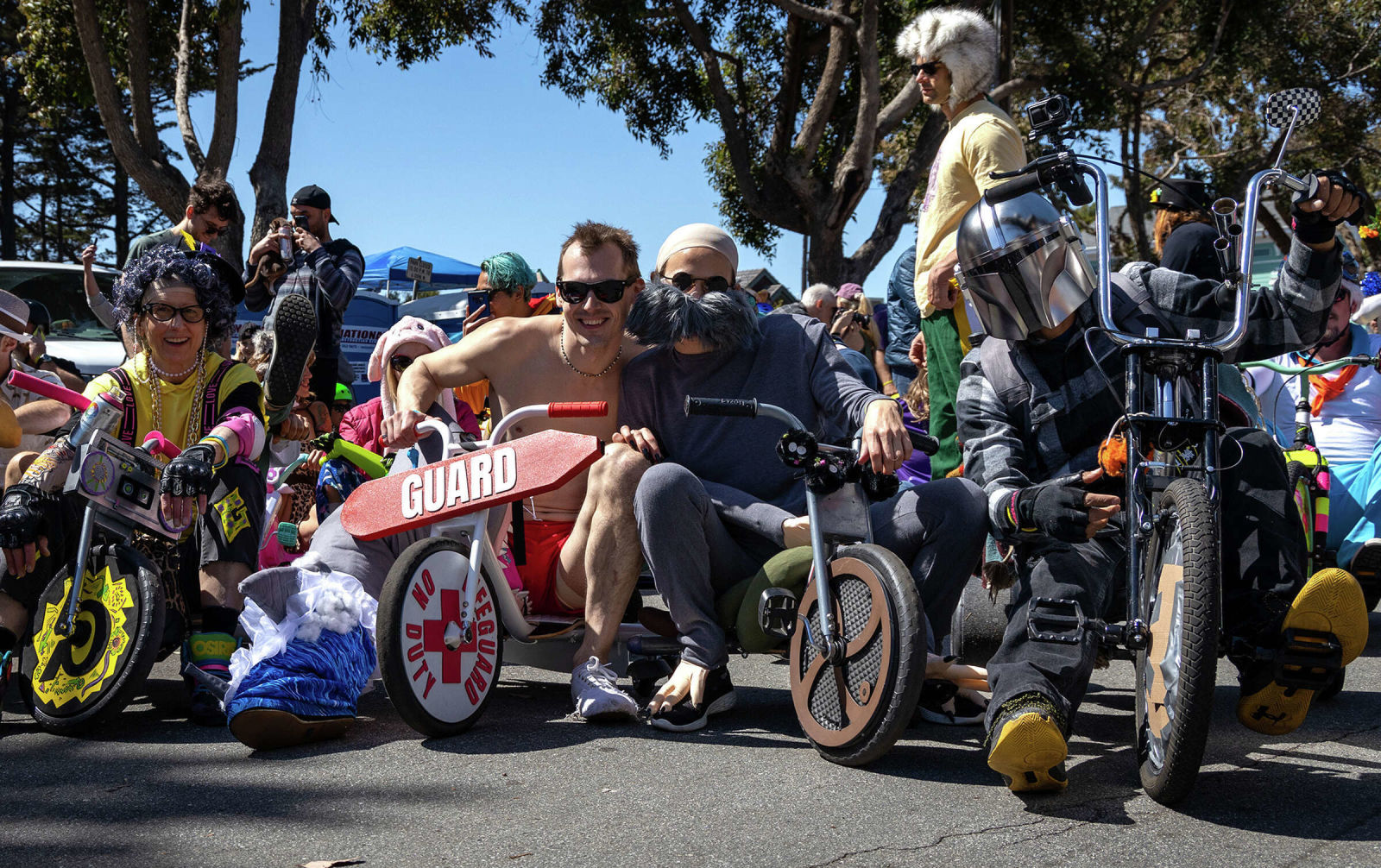people in makeshift &quot;big wheel&quot; vehicles prepare to bomb down a hill