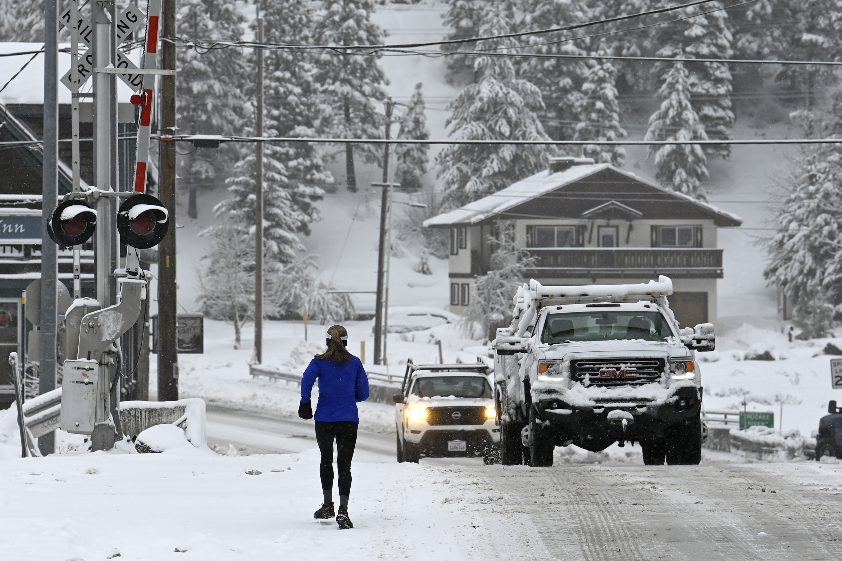 Woman runs down snowy street as trucks drive by