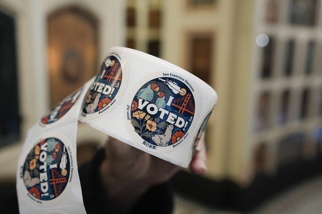 A roll of &quot;I Voted&quot; stickers featuring San Francisco landmarks is held up with an unfocused background.