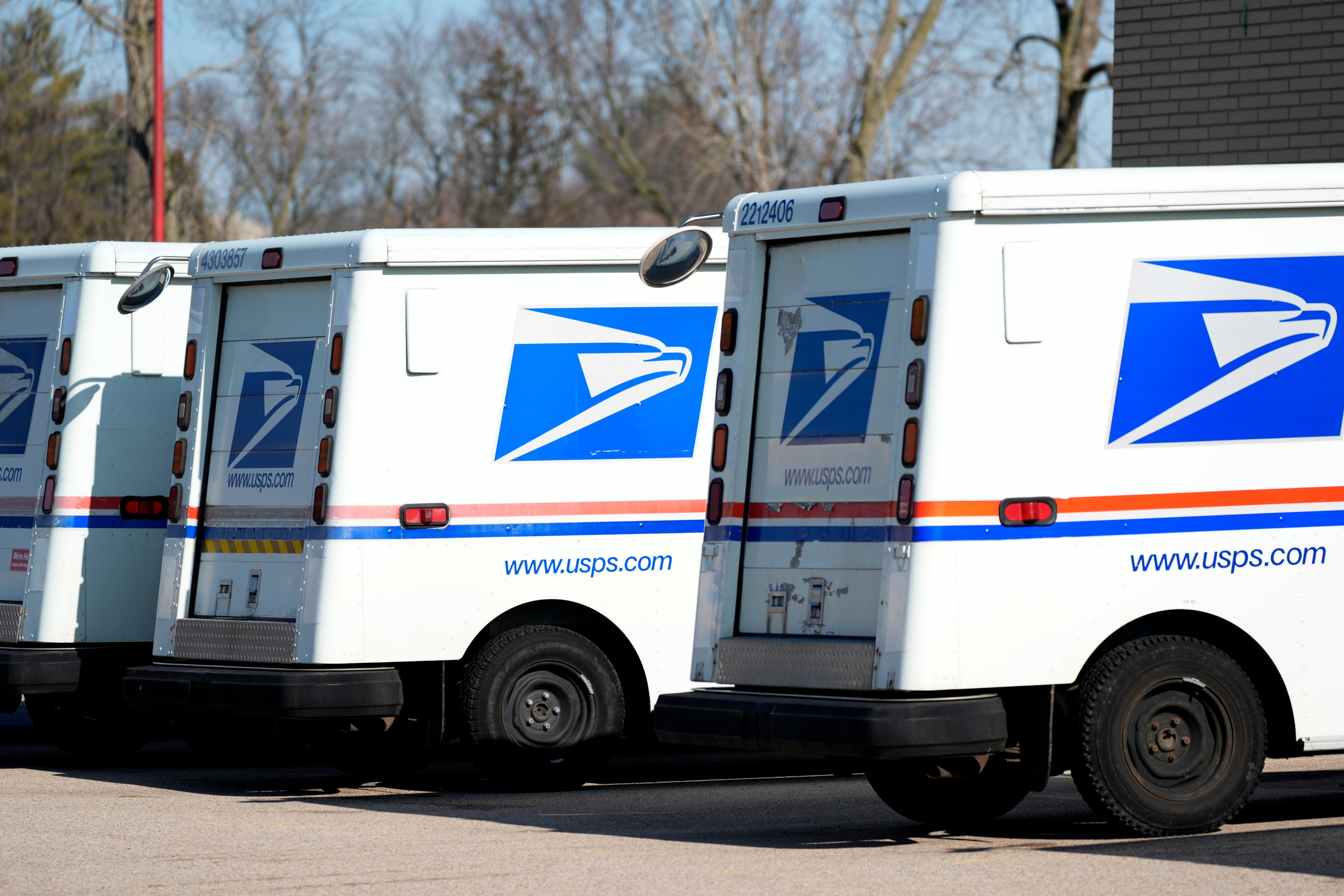 A row of USPS mail delivery trucks parked side-by-side.