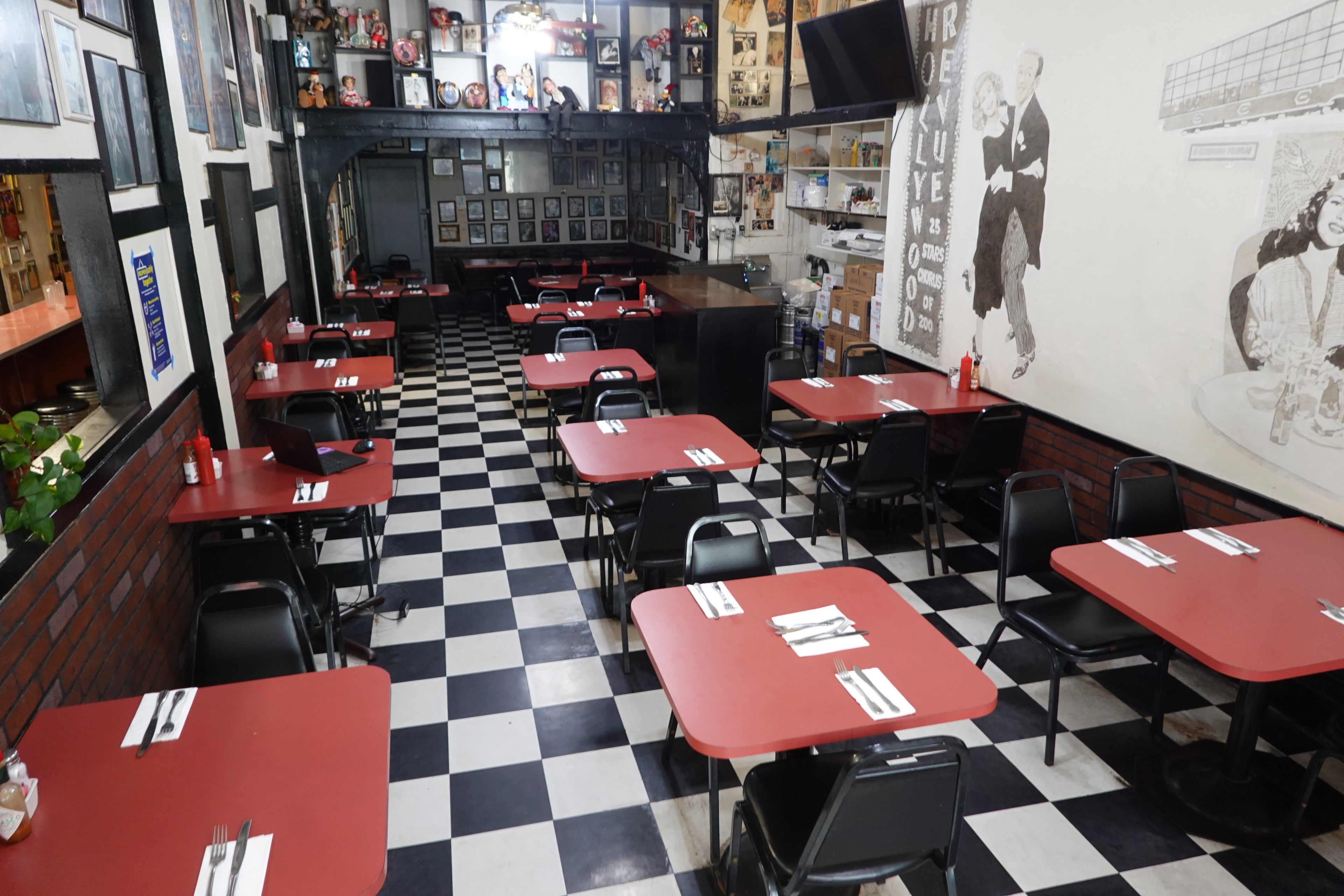 A retro diner with checkered floors, red tables, and nostalgic wall decor.