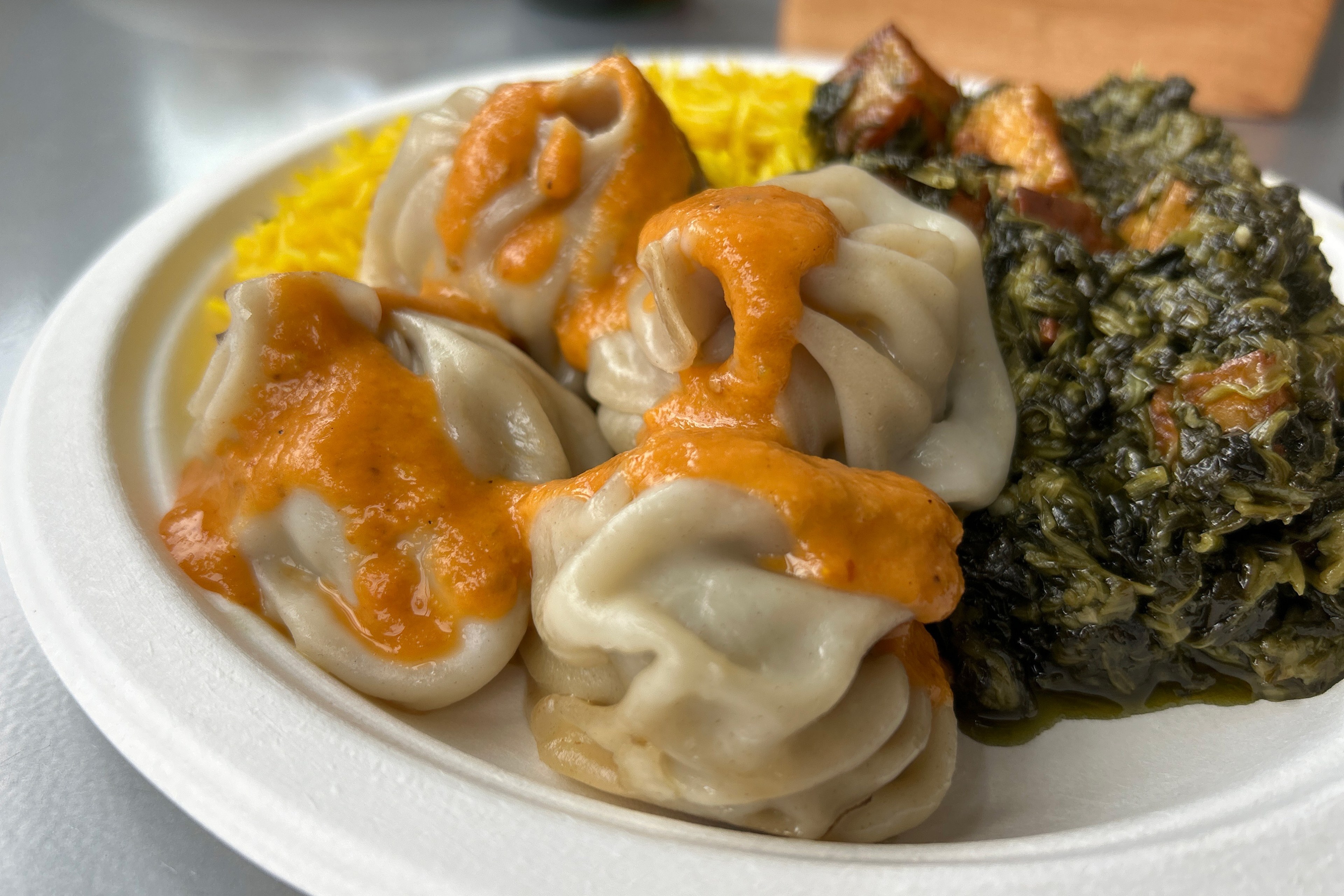 a plate of dumplings with orange sauce drizzled on them