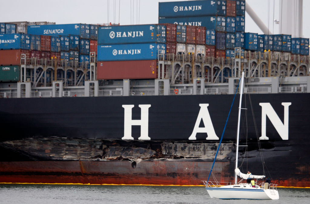 A sailboat cruises past the heavily-damaged Cosco Busan while it's cargo is removed at the Port of Oakland in Oakland, Calif. on Saturday, Nov. 10, 2007. The 810-foot long vessel, which struck a Bay Bridge tower in heavy fog Wednesday and spilled 58,000 gallons of oil into the bay, was towed back to port Friday night so it's cargo could be off-loaded.