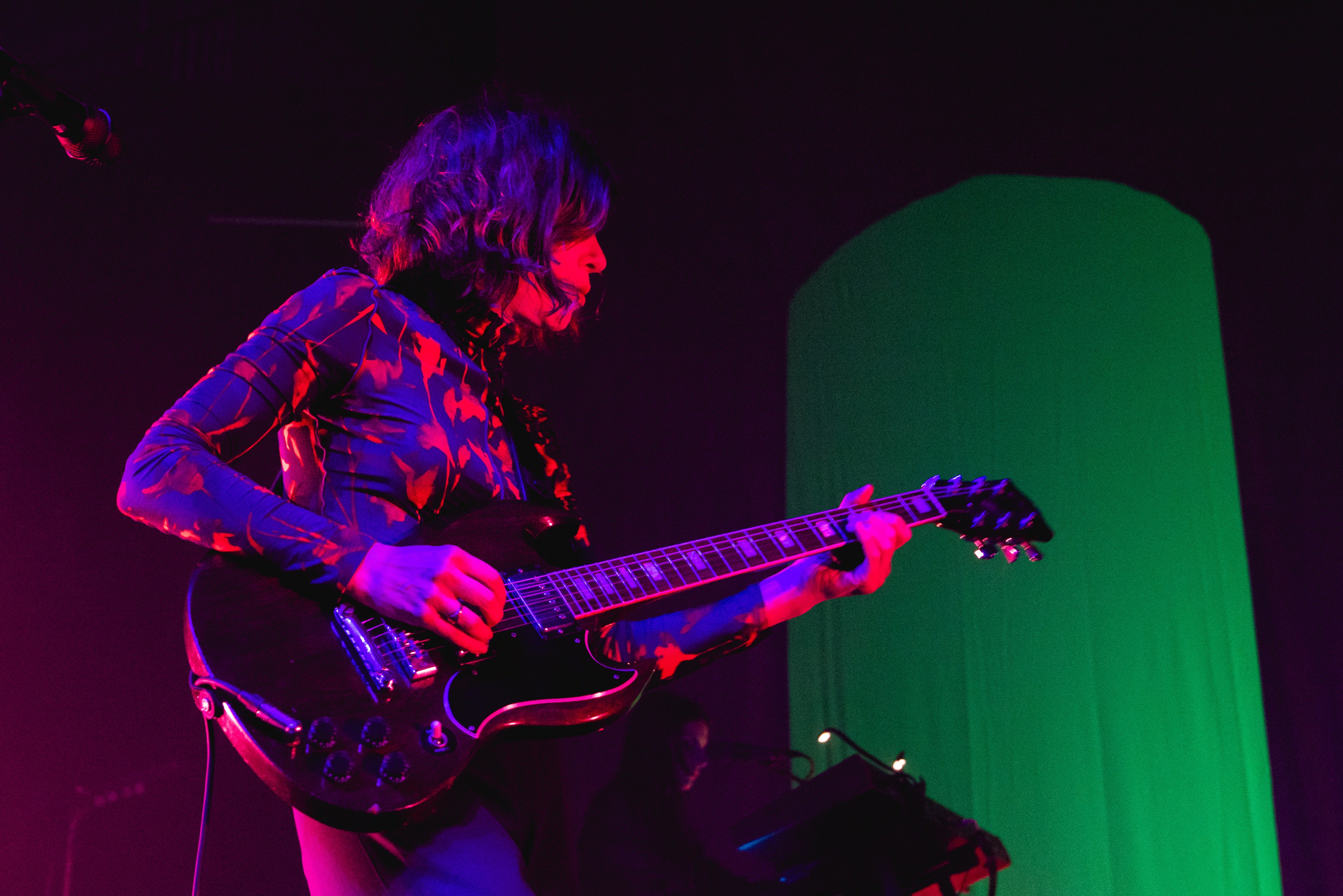 a female guitarist in profile lit in blue and red stage lights
