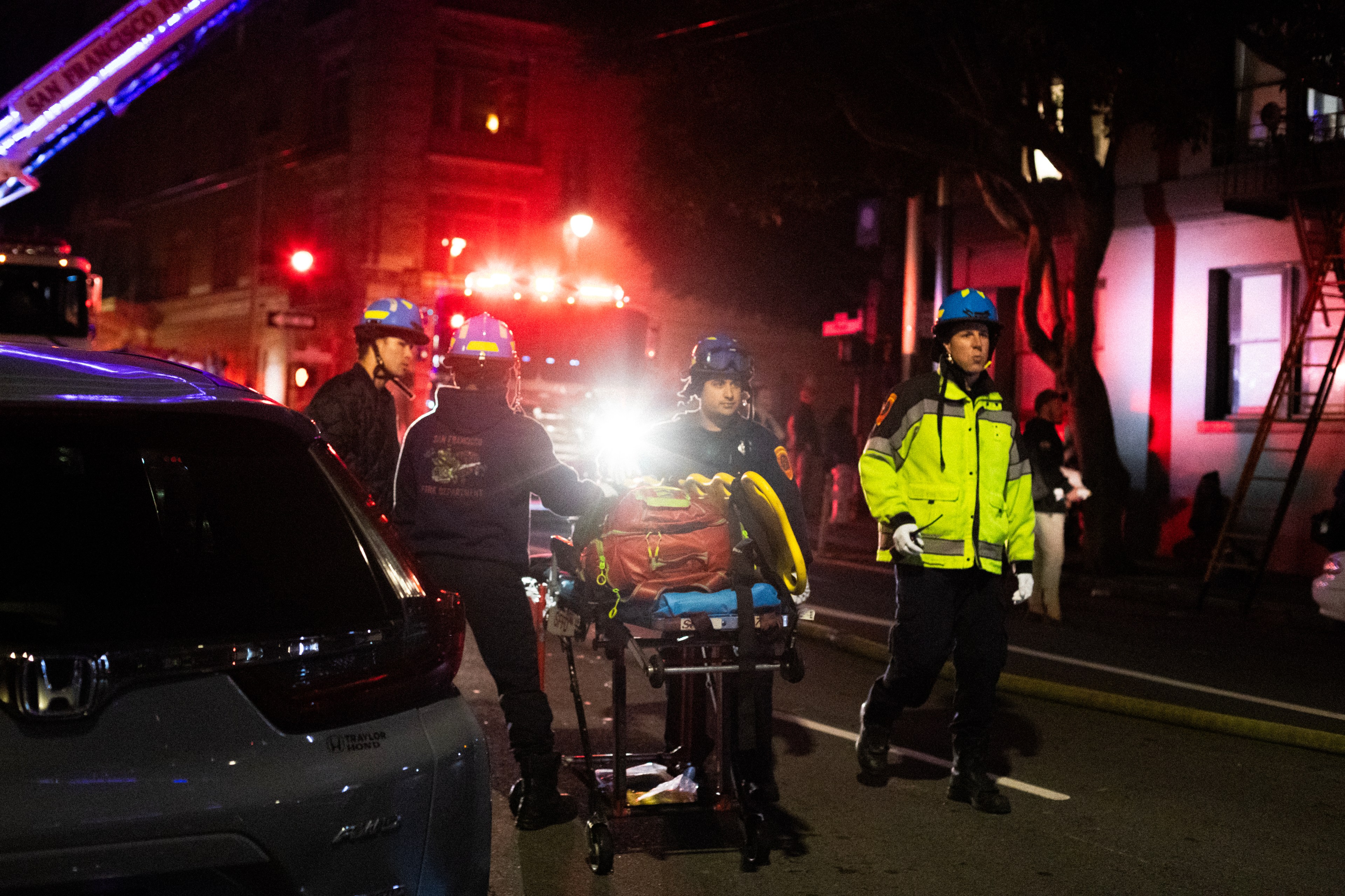 First responders stand by a stretcher outside an apartment building at night.