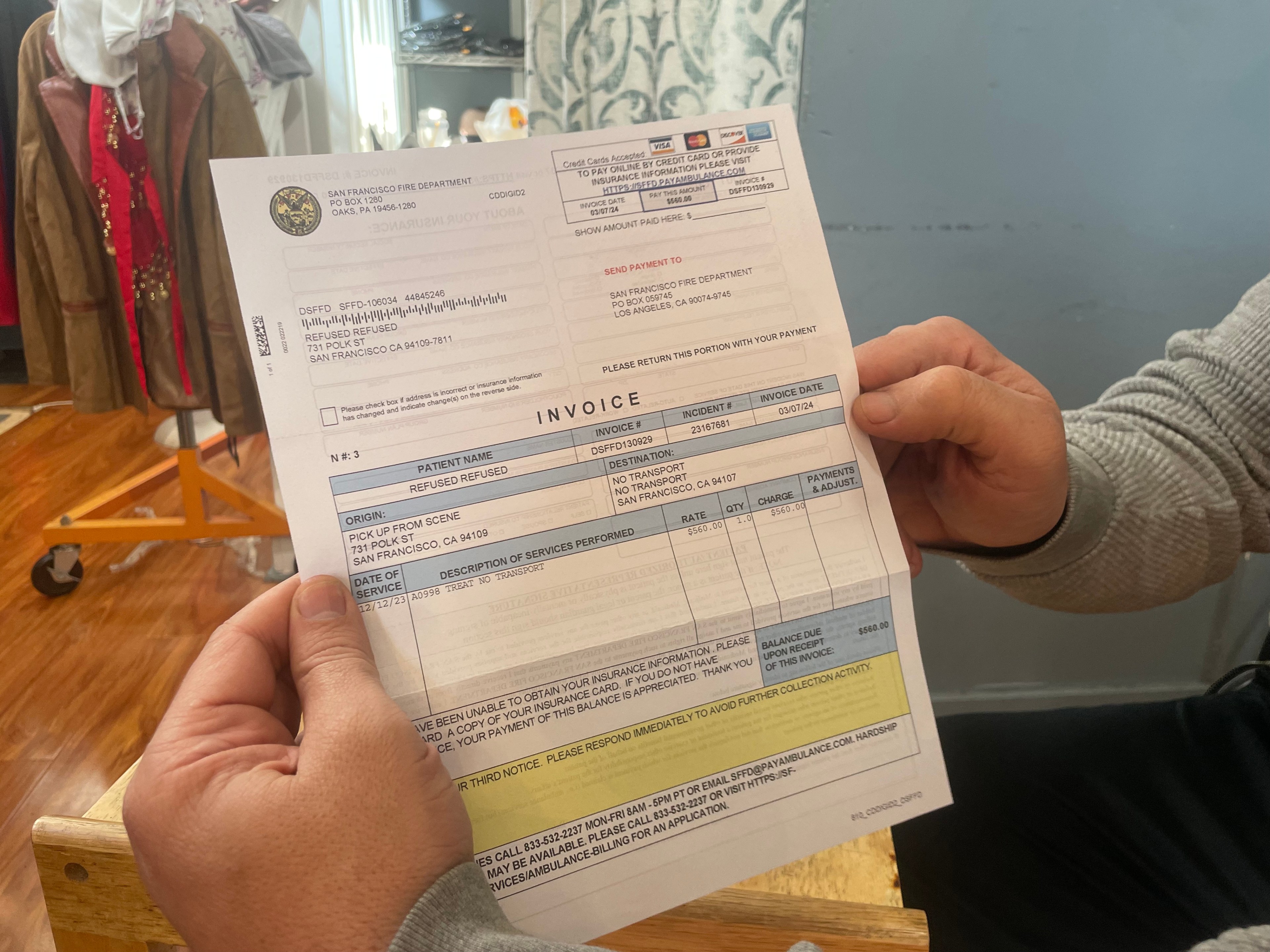 A person is holding an ambulance service invoice from the San Francisco Fire Department.