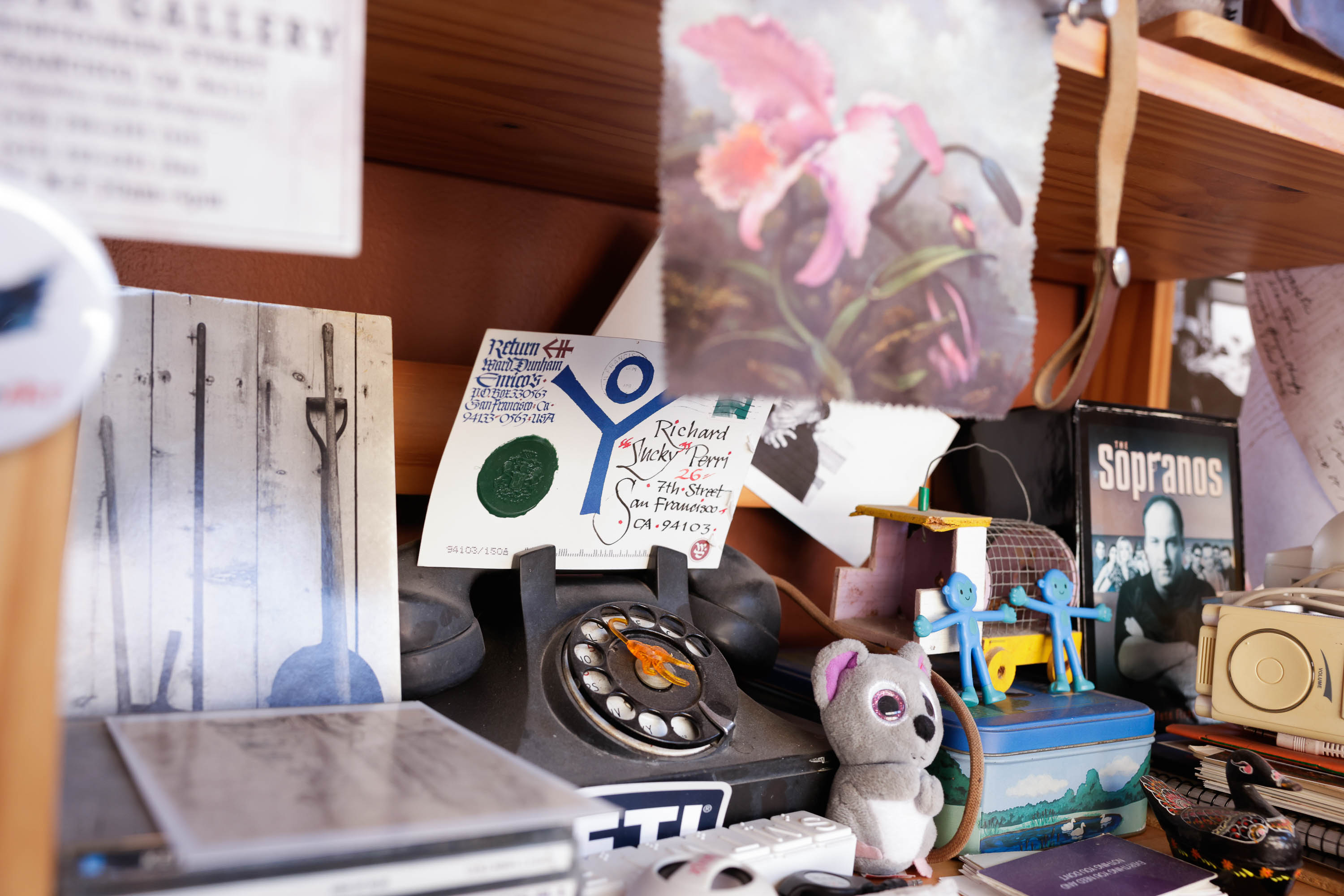 A cluttered shelf with a vintage phone, toys, a DVD box, and various memorabilia.