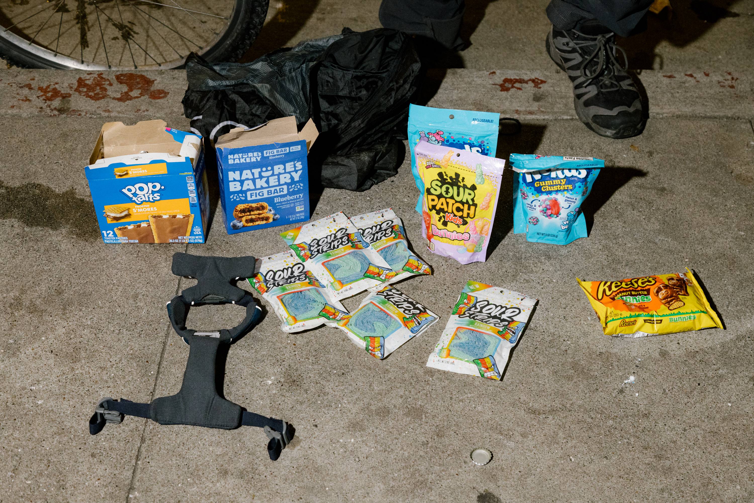 Assorted snacks and candy scattered on the ground, including Pop-Tarts, with a person's shoe visible.